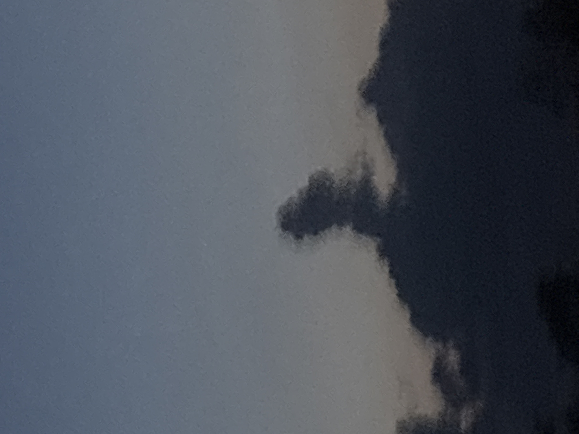 The image shows a portion of the sky in Plovdiv, Bulgaria, with varying cloud formations. The sky transitions from a lighter gray on the left to a darker, almost black, mass of clouds on the right. A smaller, distinct cloud formation protrudes from the larger, darker cloud mass. The environment is limited to the sky.