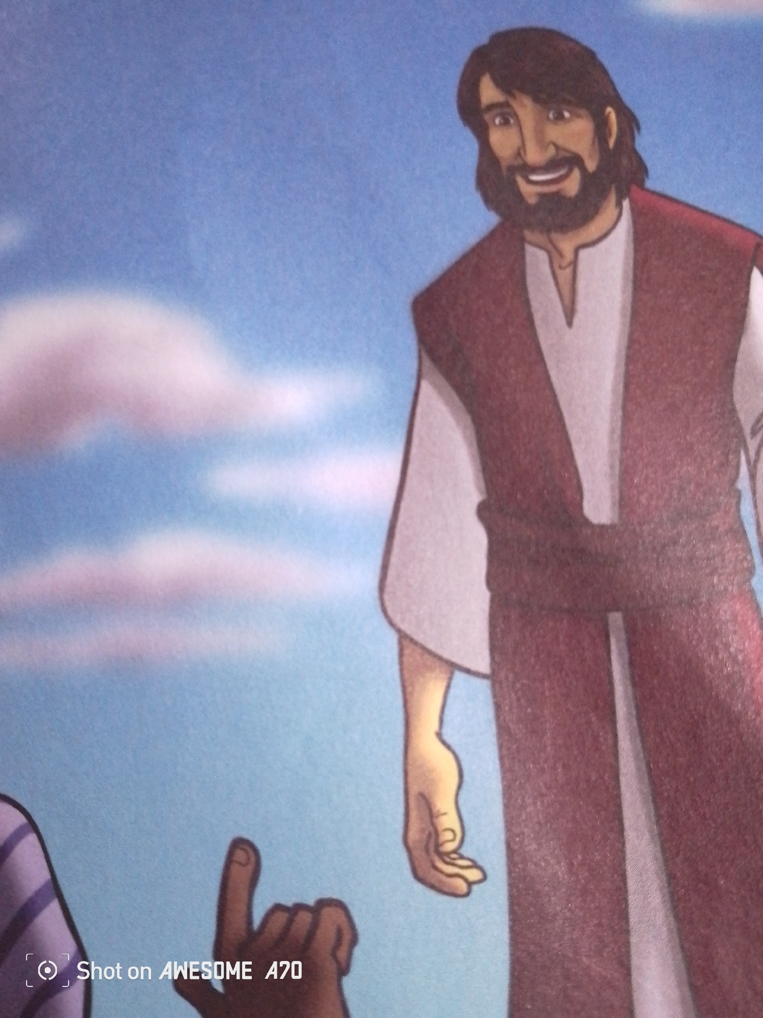 This is a close-up, angled, eye-level shot of a cartoon illustration set against a blue sky with soft, pink-tinged clouds. The main subject, positioned on the right side of the frame, is a man depicted with dark hair and a beard, smiling and wearing a white tunic and a maroon robe cinched with a darker maroon belt. His right arm is extended towards the left side of the frame, with his hand open. On the far left of the frame, a hand with a single extended finger is visible, appearing to point upwards. The lower left corner of the image displays a watermark that reads "Shot on AWESOME A70". The overall scene is suggestive of a religious or narrative illustration, possibly depicting a benevolent figure interacting with someone below. There are no discernible elements within the image that place it specifically within the city of Jalingo, Nigeria.