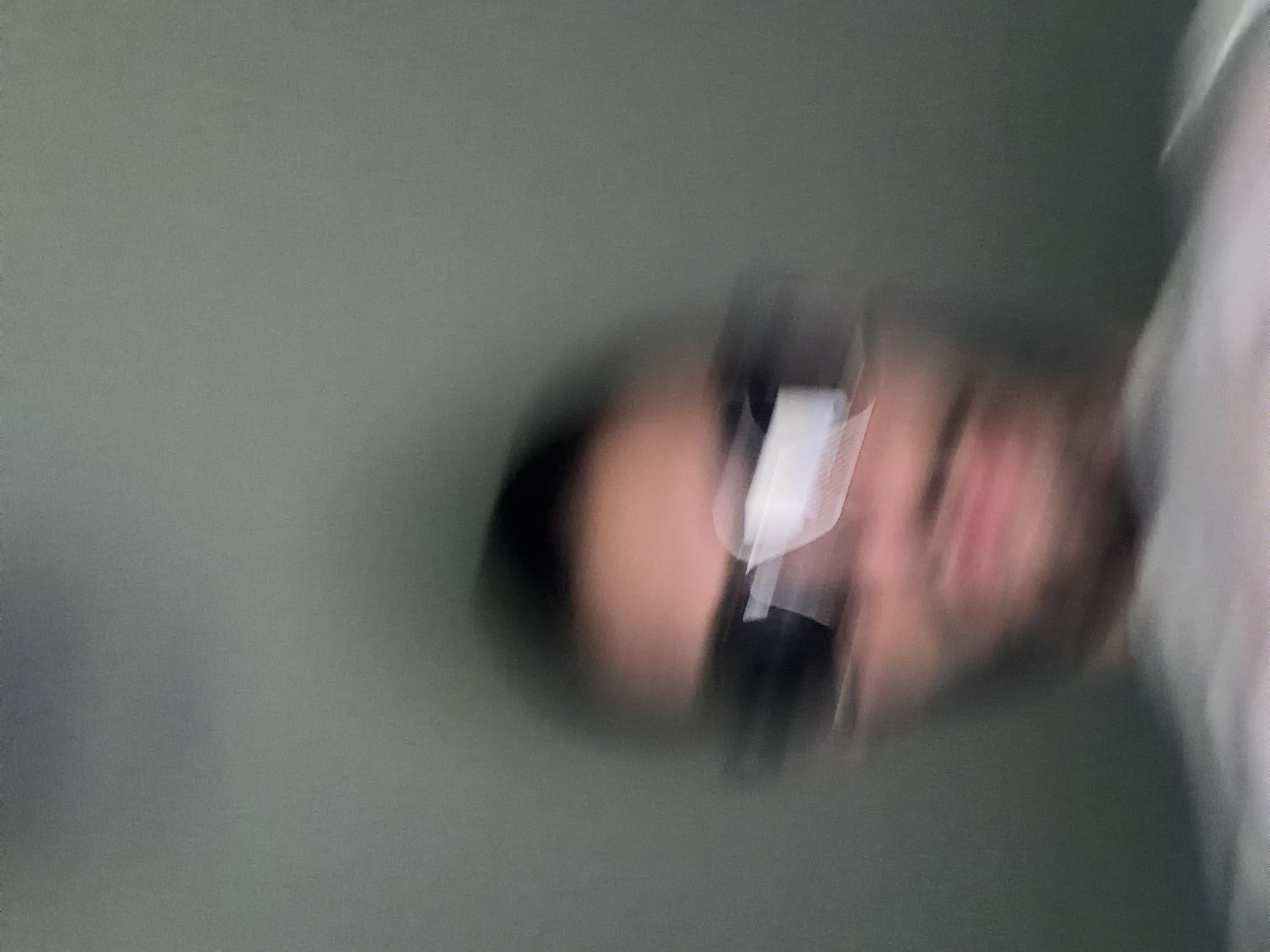 The image is blurry, depicting a person wearing sunglasses. The person is oriented sideways in the frame. The background is a muted, gray color. It is not possible to determine the location in Plovdiv, Bulgaria, or any other specific details due to the blurriness of the image.