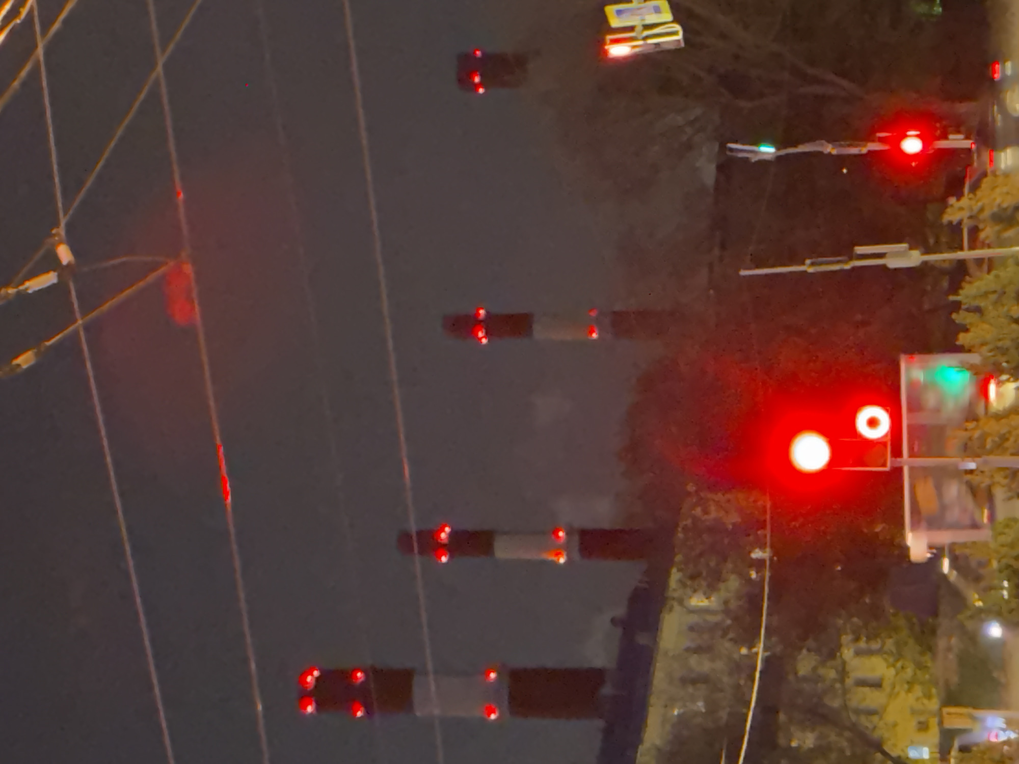 The image depicts a nighttime scene with several red traffic lights. There are also several striped railroad crossing barriers with flashing red lights at each end. A car with headlights is visible. The location is Moscow, Russia.