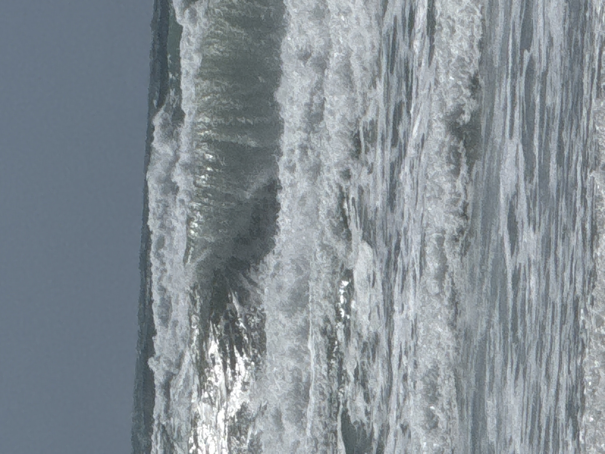 The image depicts waves crashing on a beach in Bat Yam, Israel. The sky is overcast and grey. The waves are turbulent and foamy.