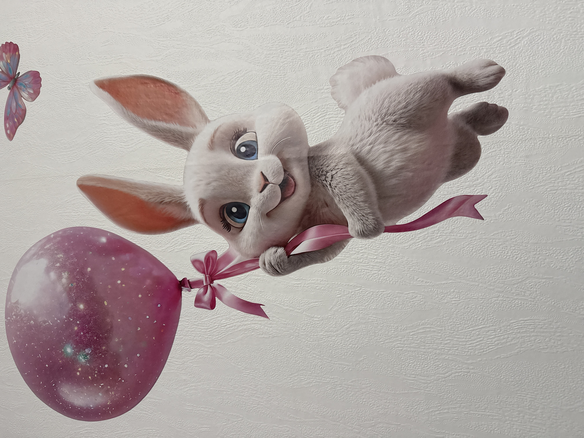 An animated, white rabbit with blue eyes and a pink ribbon tied to a large, pink, glittery balloon floats against a white, textured wall. The rabbit is holding the balloon's string with its right paw. A small, pink butterfly is visible in the upper right corner of the image.