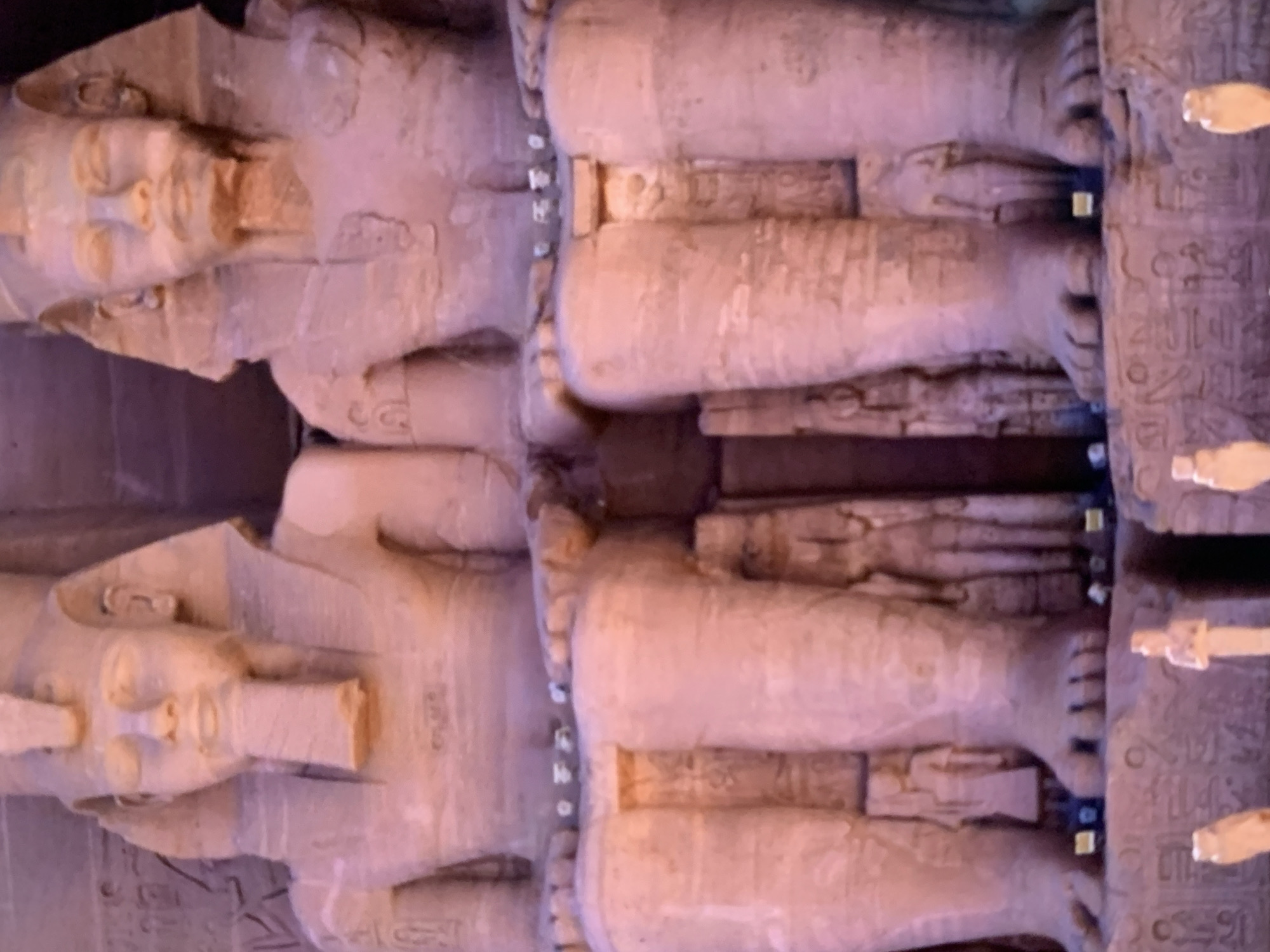 The image shows two colossal statues, likely depicting ancient pharaohs, carved from stone. They are seated with their hands resting on their laps. The statues have elaborate headdresses and ornate collars. Hieroglyphs are visible on the bases of the statues and on smaller figures positioned between their legs. The overall scene suggests an archaeological site or a monument dedicated to ancient Egyptian history. The image does not provide any information or context related to Stavropol, Russia.