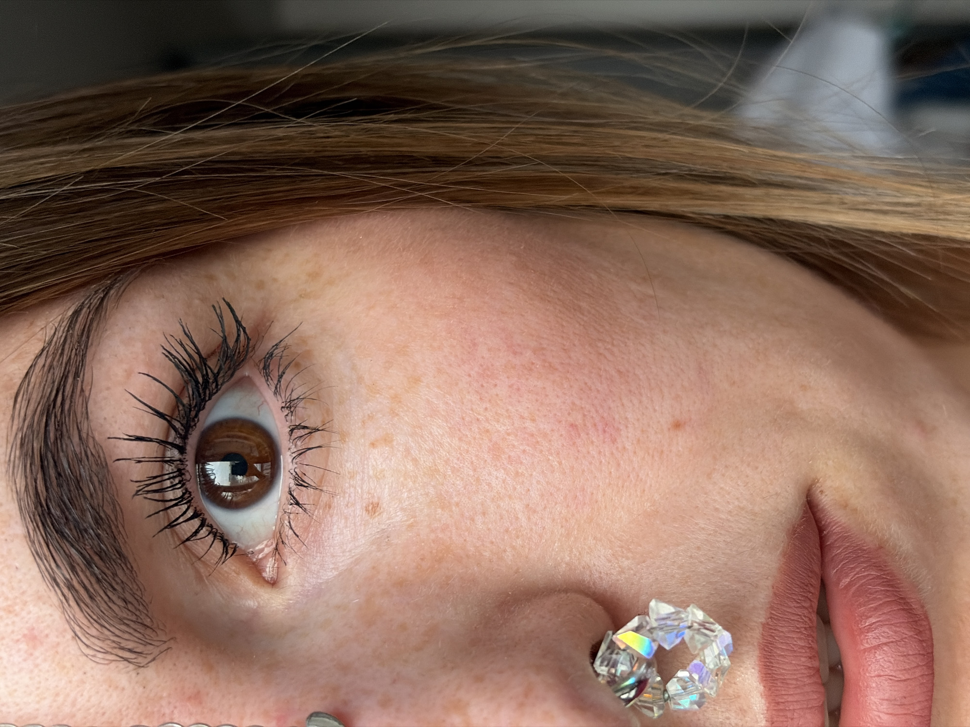 An eye of a person is looking into the camera, and mascara is on the eyelashes. The person is wearing earrings. The location of the photo is unknown and not relevant to Izhevsk, Russia.