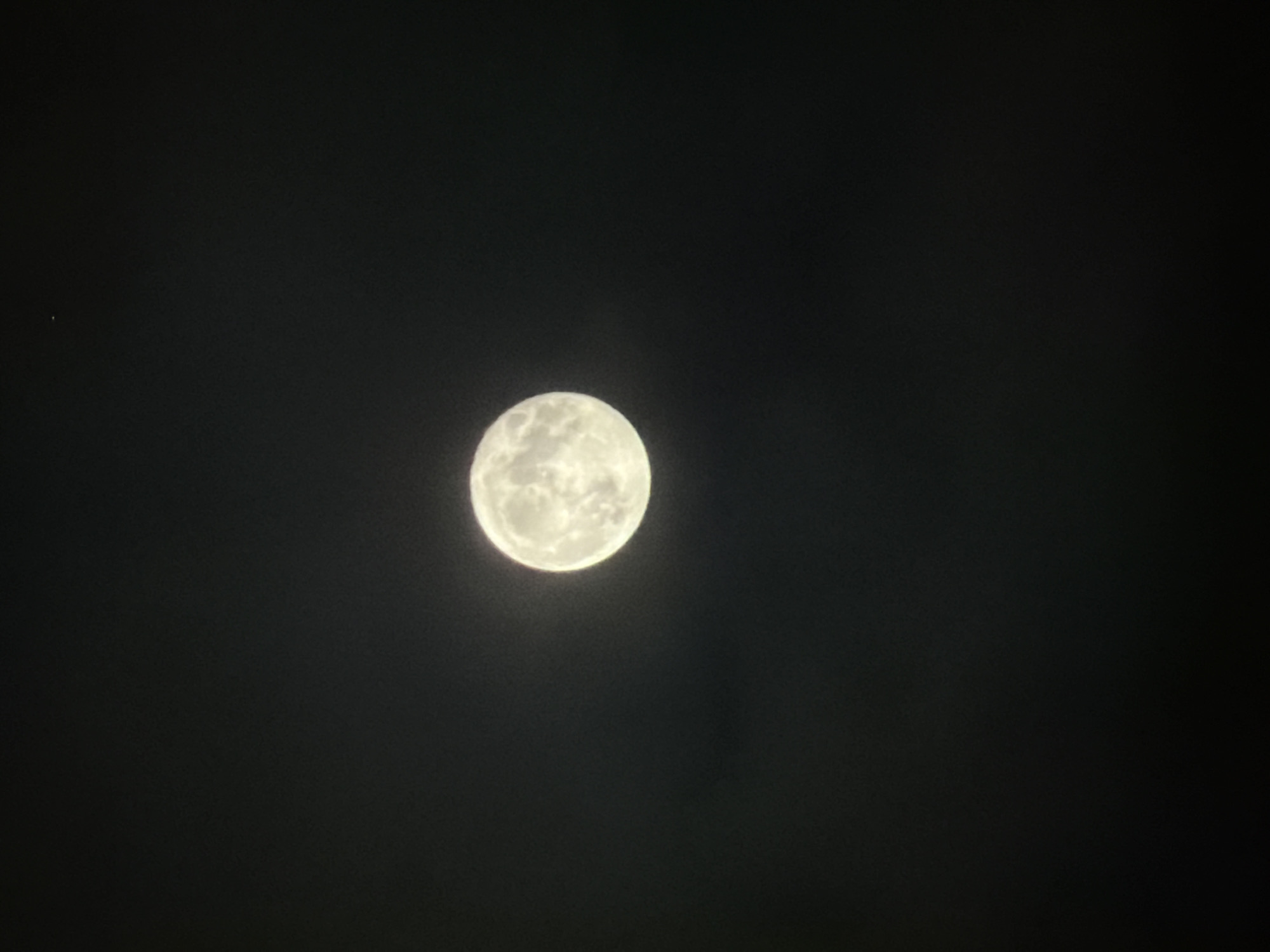 A full moon is centered in the black sky. A small, faint star or planet is visible in the upper-left corner. The location is unknown.