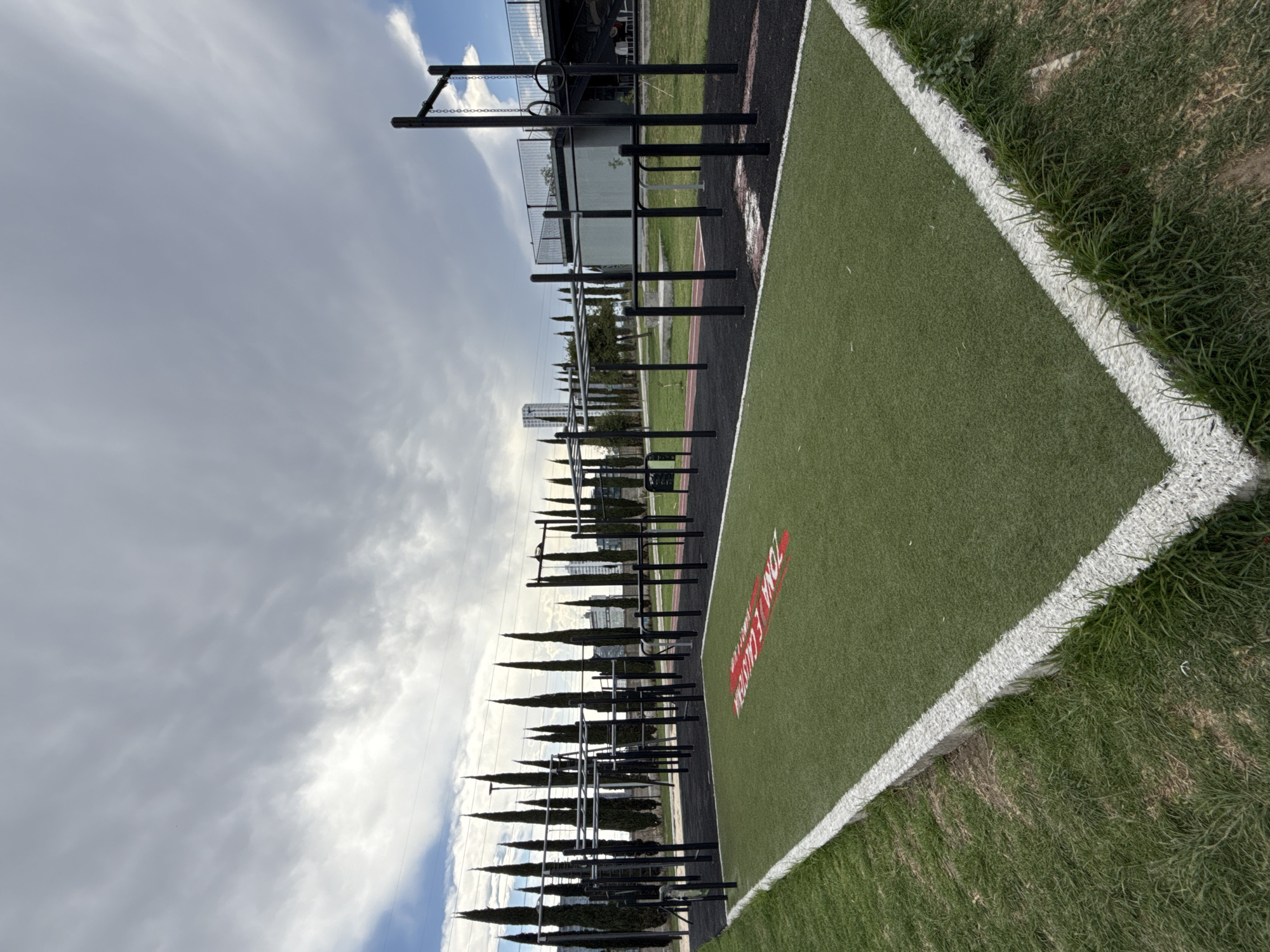 The image shows an outdoor workout area with monkey bars, pull-up bars, and other fitness equipment, adjacent to an artificial turf area with white boundary lines and the words "ZONA FENIXX" in red. The location appears to be in a park setting in the city of Puebla, Mexico, as it is labeled on the artificial turf. The sky is cloudy.