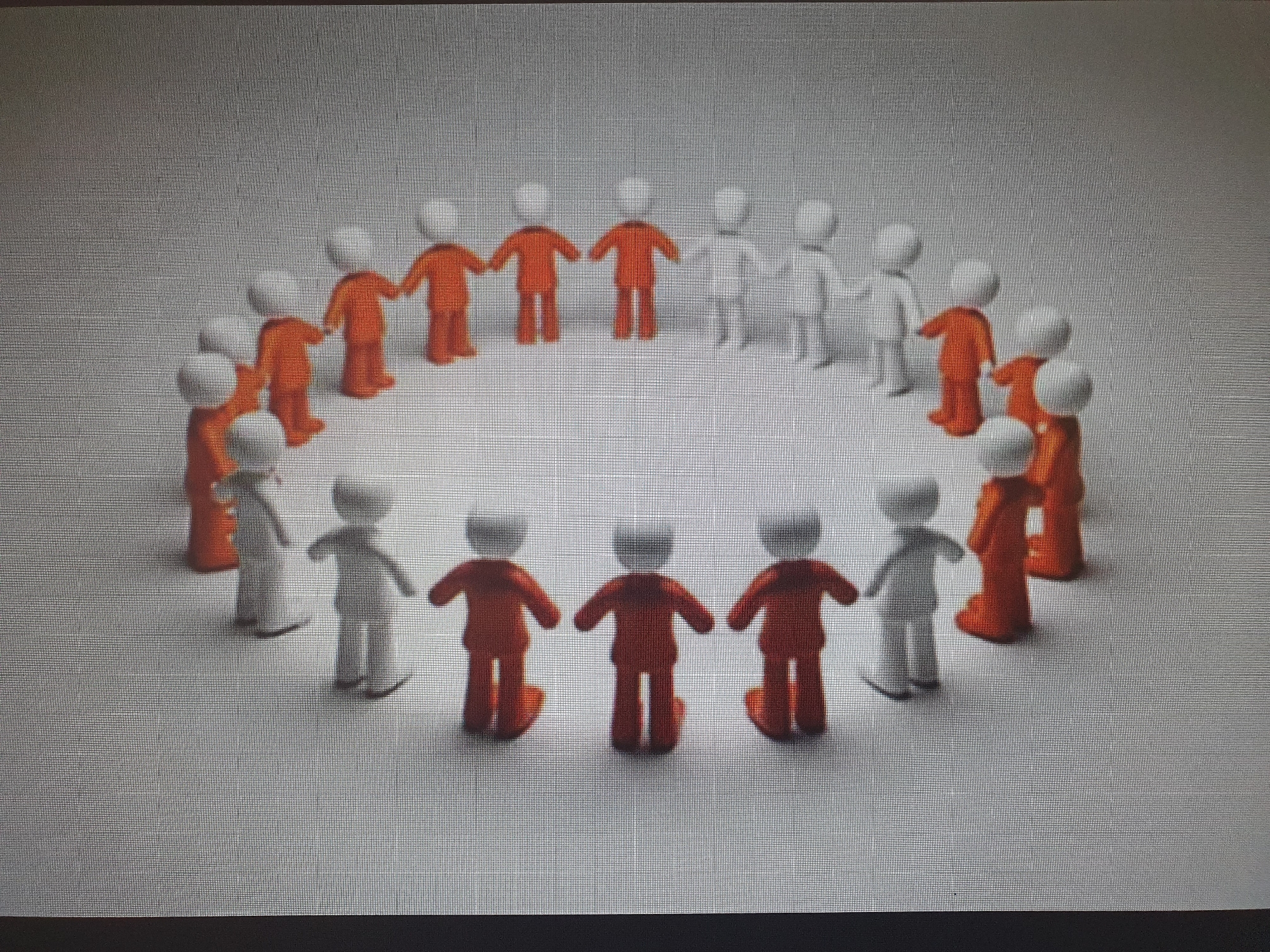 The image depicts a circle of simplified, humanoid figures, with alternating orange and white figures. The figures are standing and appear to be holding hands, forming a continuous chain. The background is a plain, light gray surface with subtle shading, creating a sense of depth. There are no discernible architectural features or elements that would indicate a specific location in Tashkent, Uzbekistan, or any other city. The scene is rendered in a clean, minimalist style.