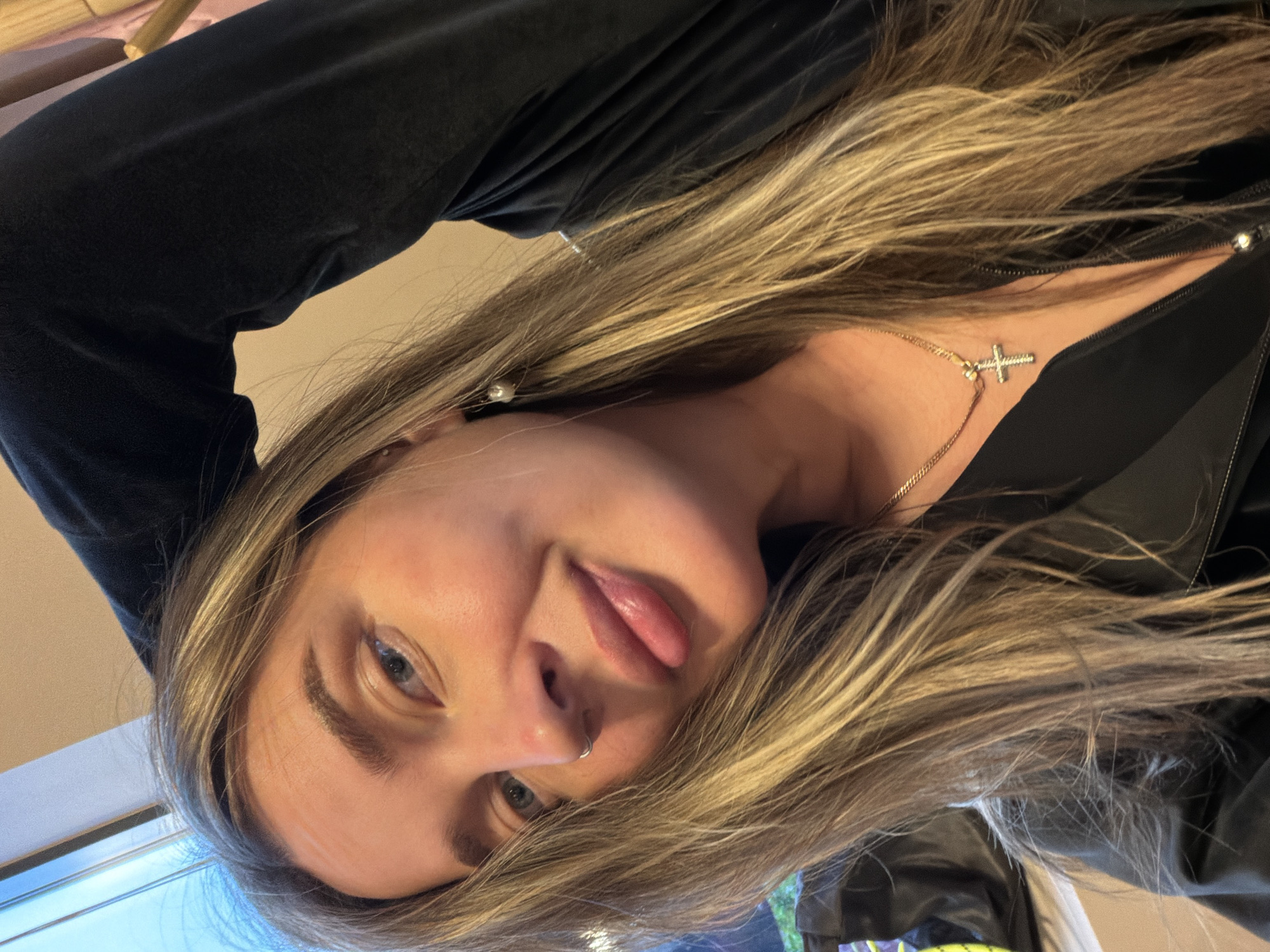 A woman with blonde hair, light skin, and blue eyes is looking at the camera. She is wearing a black jacket and a necklace with a cross pendant. There is no evidence to suggest this image was taken in Khimki, Russia.