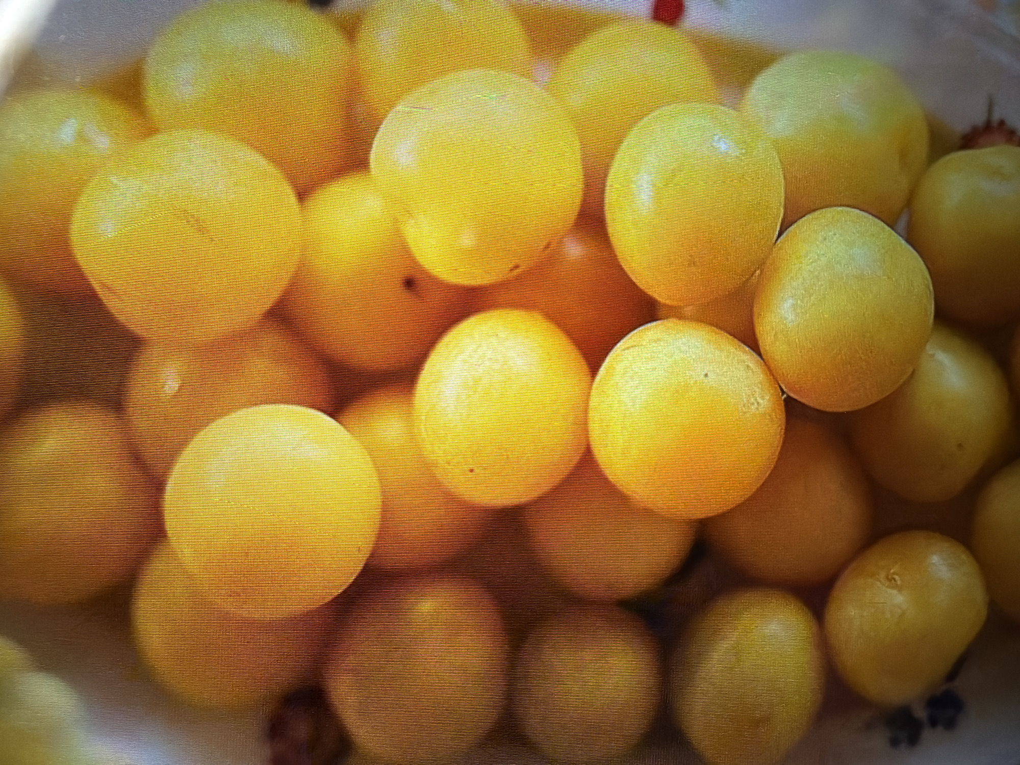 This is a close-up, high-angle shot of a pile of yellow plums. The plums are round and have a smooth, shiny skin. Some of the plums are in sharp focus, while others are blurred, creating a sense of depth. The background is a soft, out-of-focus blur of warm colors, suggesting a natural setting or a diffused light source. There are no people or specific Moscow landmarks visible in the image.