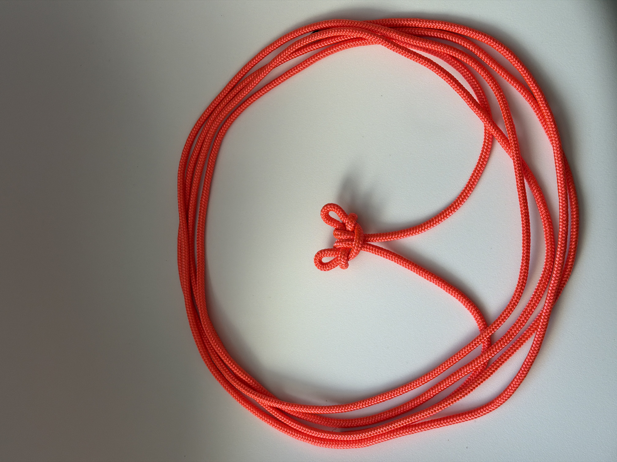 The image depicts an orange rope coiled on a white surface. A knot is tied in the middle section of the rope. The left side of the surface appears to be in shadow. There is no indication of the image location being Berezniki, Russia or any human presence in the image.