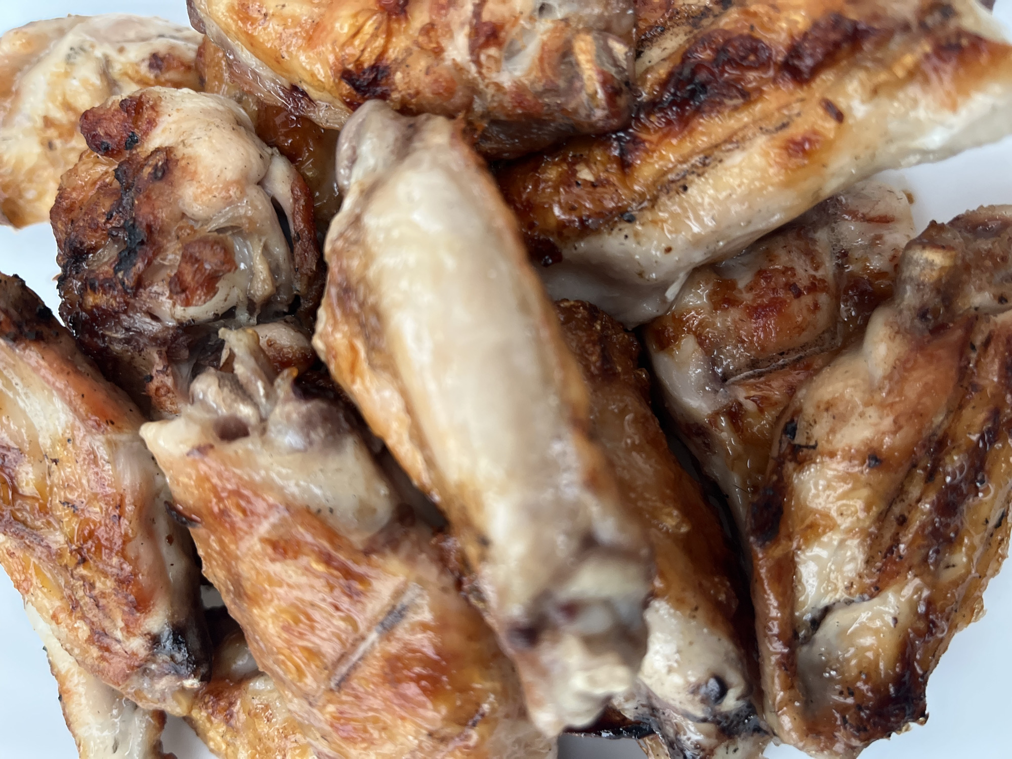 The image shows a close-up of a pile of cooked chicken wings. The wings have a golden-brown, slightly charred appearance, indicating they were likely grilled or baked. The meat appears moist and succulent. No people, identifiable objects, or environmental details are present in the image to determine the location in the city of Chaikovsky, Russia.