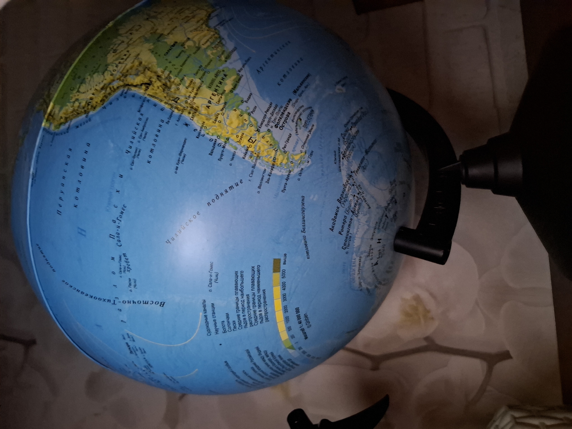 The image shows a globe with South America facing the viewer. The Pacific Ocean is visible on the left and the Atlantic on the right. Parts of North America and Antarctica are visible as well. The globe rests on a stand. The scale on the globe indicates a scale of 1:40,000,000. Text on the globe is in Russian.
The location is not in the city of Amzya, Russia. The location is not visible.