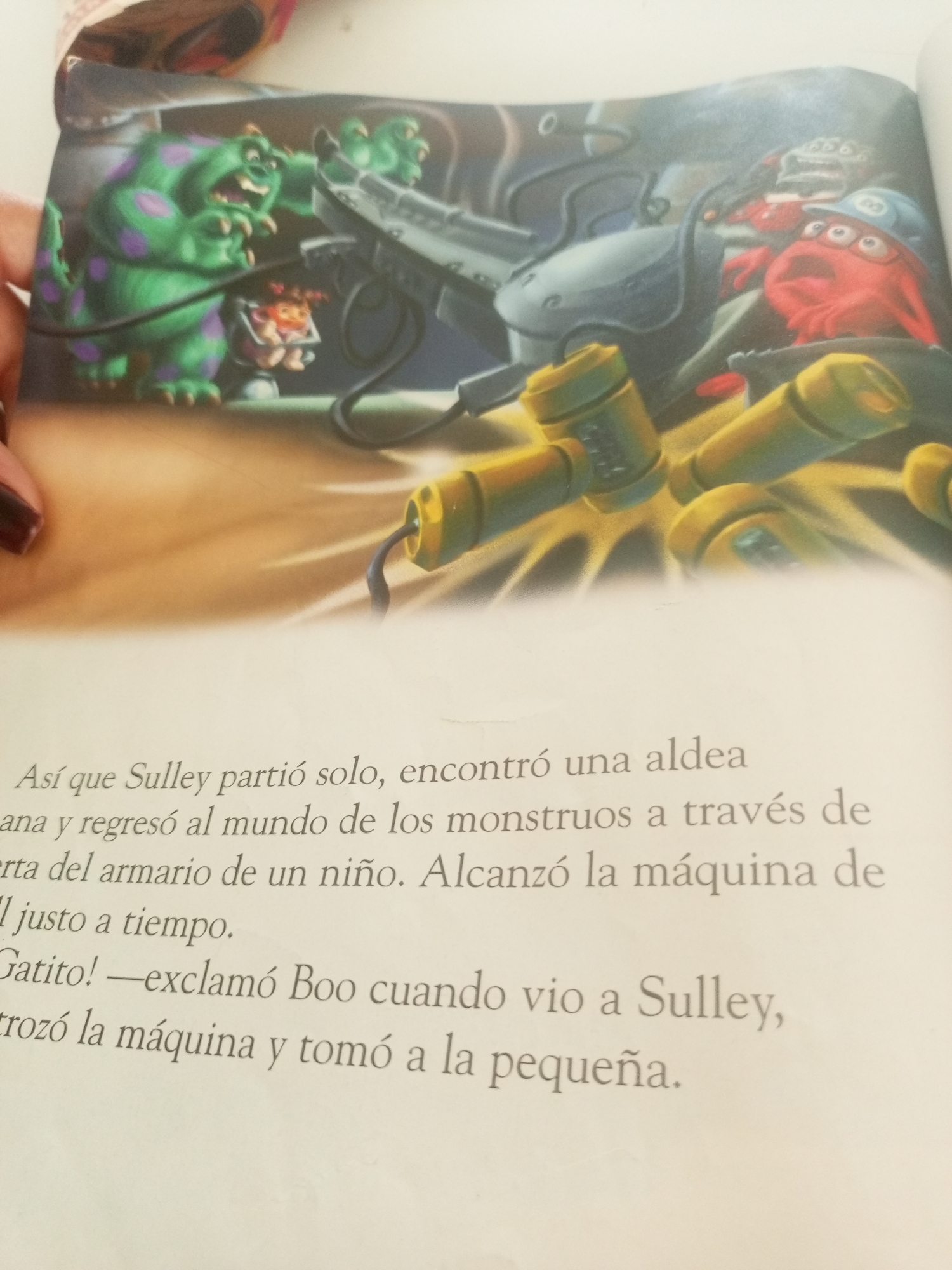 The image depicts an illustration from a children's book, featuring characters from Monsters, Inc. On the left, a large green monster with purple spots, identified as Sulley, is shown. Next to him, a small human child, Boo, is visible inside a contraption. To the right, a red, cycloptic monster with glasses is looking on. The background shows mechanical elements and a dark, industrial-like environment, consistent with the movie's aesthetic.
Below the illustration, there is Spanish text that reads: "Así que Sulley partió solo, encontró una aldea" (So Sulley left alone, he found a village), "ana y regresó al mundo de los monstruos a través de" (ana and returned to the monster world through), "erta del armario de un niño. Alcanzó la máquina de" (the closet of a child. He reached the machine of), "ll justo a tiempo." (ll just in time.), "Gatito! —exclamó Boo cuando vio a Sulley," (Kitty! - exclaimed Boo when she saw Sulley,), "trozó la máquina y tomó a la pequeña." (trozed the machine and took the little one.).
The question asks for the location in La Tagua, Venezuela. However, the image and its context are clearly from the fictional world of Monsters, Inc. and do not depict any real-world location, including La Tagua, Venezuela. Therefore, it is impossible to provide details about La Tagua based on this image.