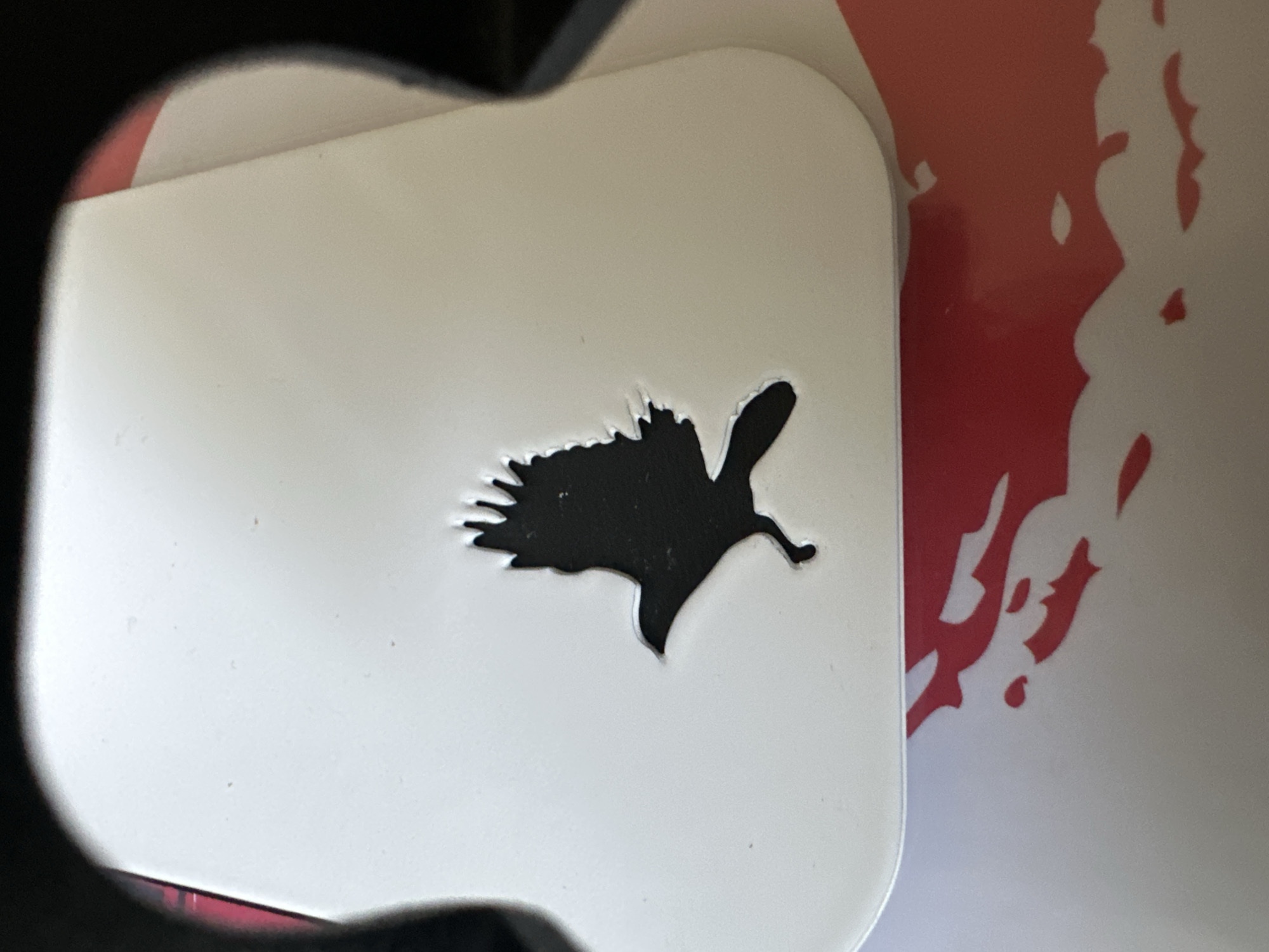 The image shows a close-up of a white object with a black silhouette of a bird in flight. The bird appears to be an eagle or a hawk, with its wings spread and its body facing left. The object is curved, suggesting it might be part of a larger item. The background is dark and out of focus. There are no people or any specific landmarks visible in the image that would indicate its location in Rostov-on-Don, Russia.