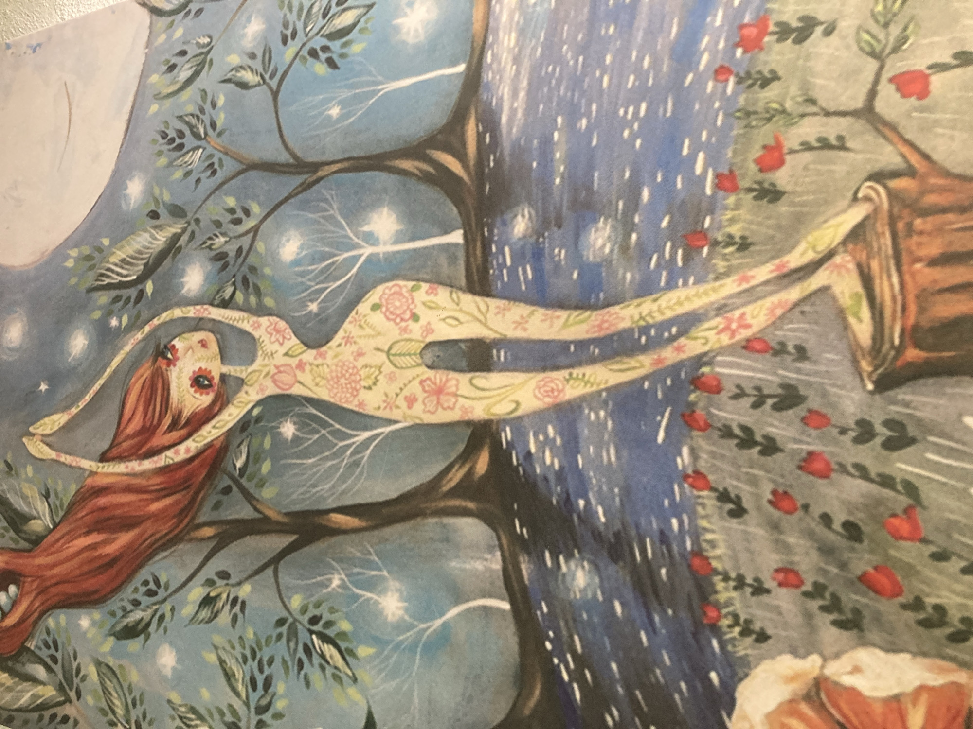 The image is a watercolor painting depicting a surreal, enchanted forest scene. A slender, anthropomorphic female figure with long, flowing red hair and body covered in floral patterns stands on a tree stump. She is reaching her arms upwards, with her body contorted in a dance-like pose. The background features stylized trees with sparse foliage against a deep blue, starry sky and a large, pale moon. A body of water with reflections of white specks runs horizontally across the mid-ground. In the foreground, a field of small red flowers, possibly tulips, is visible. There is no indication of the city of Sabadell, Spain, or any urban elements in the painting.
