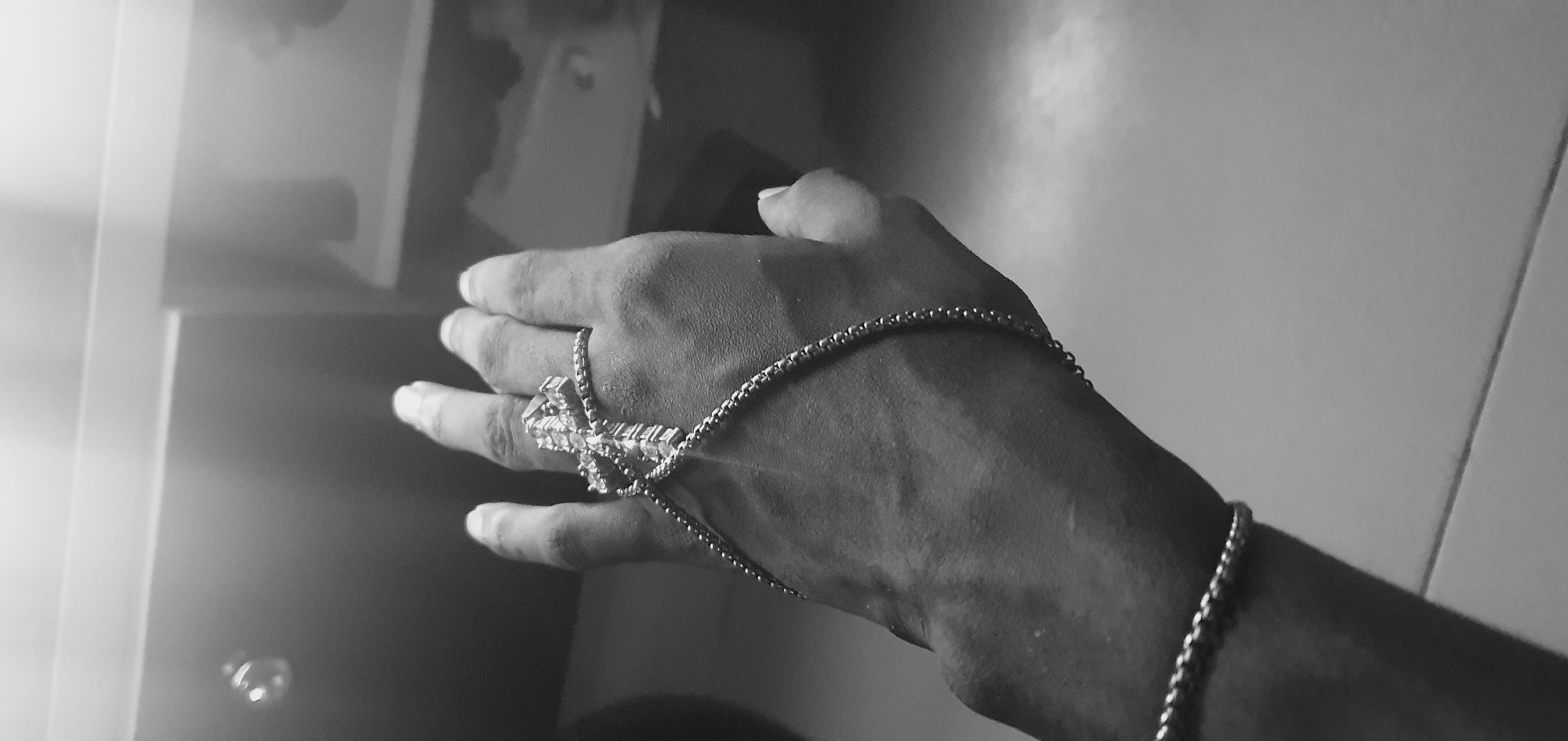 A black and white image shows a hand wearing jewelry. The jewelry includes a large ring, possibly with stones, connected by chains to a bracelet. The location is not discernible from the image, so it's impossible to ascertain if it's in Lokoja, Nigeria.