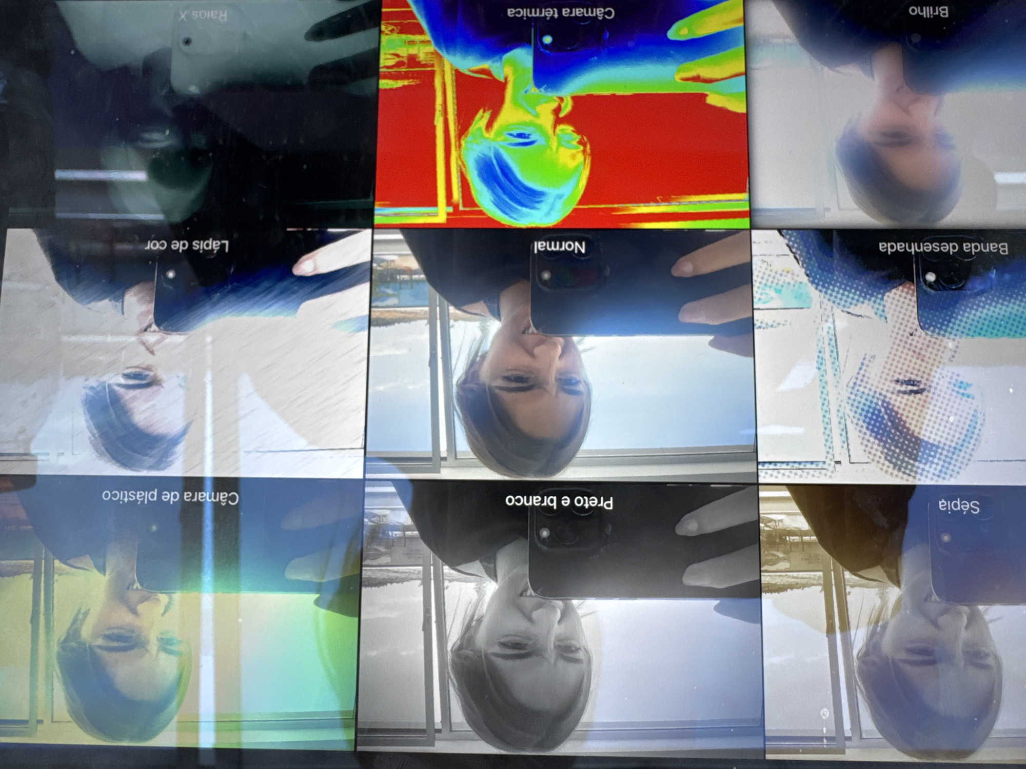 The image shows a grid of nine selfies of a woman taken with different camera filters on a mobile phone. The filters are labelled in Portuguese: "Raios X," "Câmara térmica," "Brilho," "Lápis de cor," "Normal," "Banda desenhada," "Câmara de plástico," "Preto e branco," and "Sépia." The background visible in the "Normal," "Preto e branco," and "Sépia" photos reveals a building and a coastal landscape. Based on the style of the building and the location of the woman during the shot of the window reflection, it is most likely that she is taking this picture from somewhere within the city of Torres Vedras, Portugal.