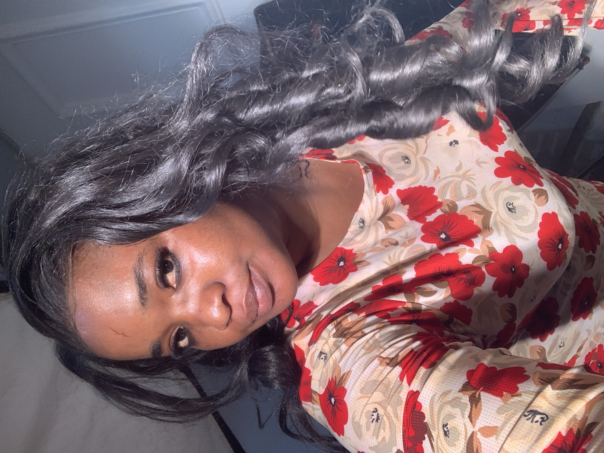 A woman with dark skin, dark hair, and wearing a patterned top is angled to the left. She is looking directly at the camera. The location is not discernible as Barakin Akawo, Nigeria, from the visual details.