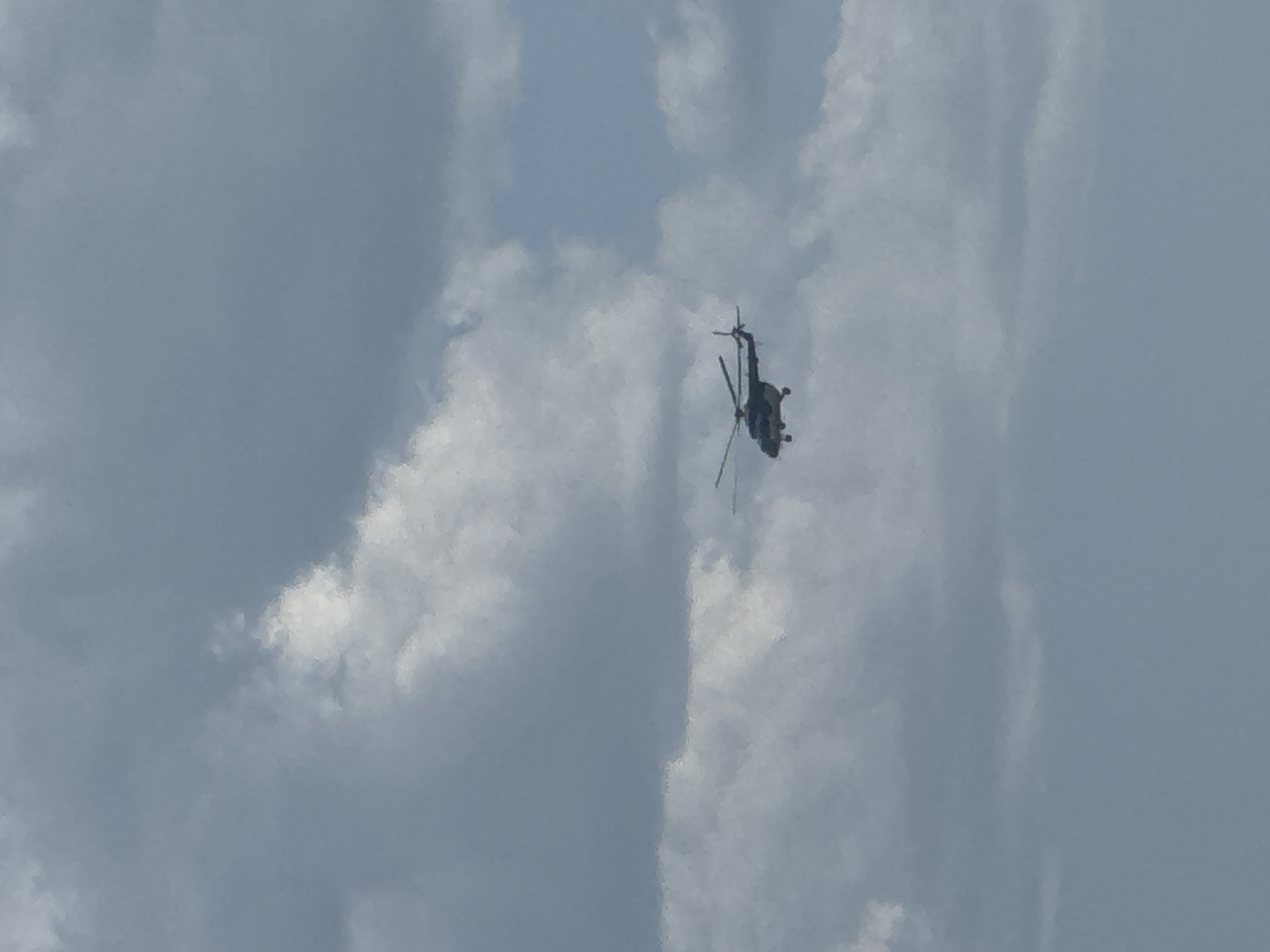 A helicopter is in the air surrounded by clouds. There is no evidence to indicate that this image was taken in Chaikovsky, Russia.