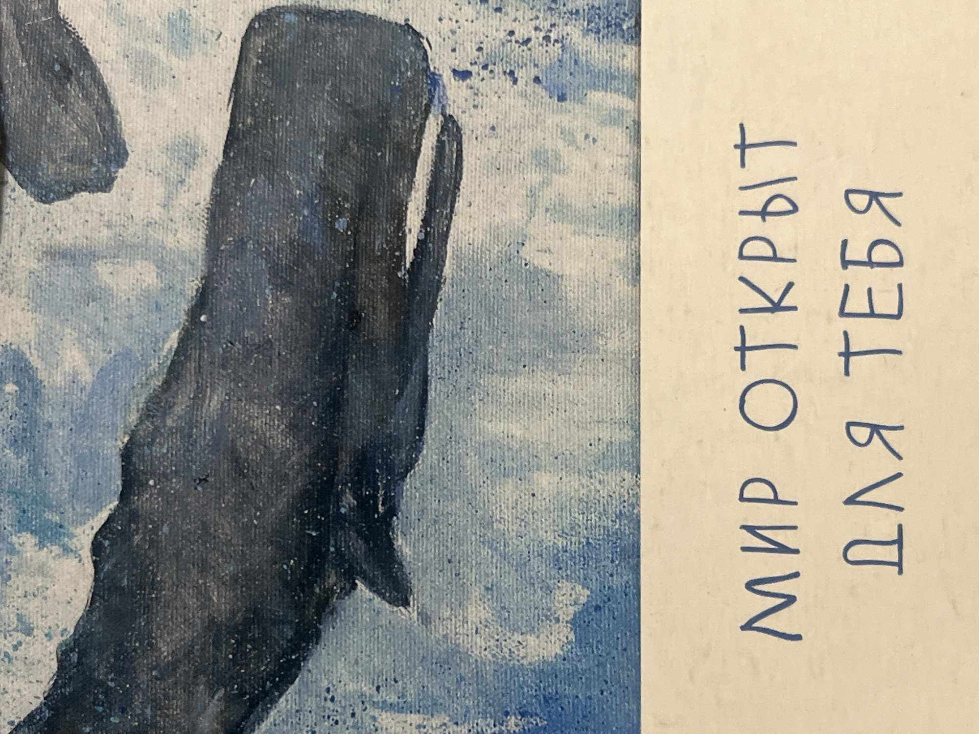 The image displays a portion of a painting featuring a dark blue whale swimming through abstract blue and white water. Below the painting, on a light-colored surface, handwritten text in blue ink reads "МИР ОТКРЫТ ДЛЯ ТЕБЯ" which translates to "The world is open for you". The image does not contain any information about the city of Chelyabinsk, Russia, or any specific location.