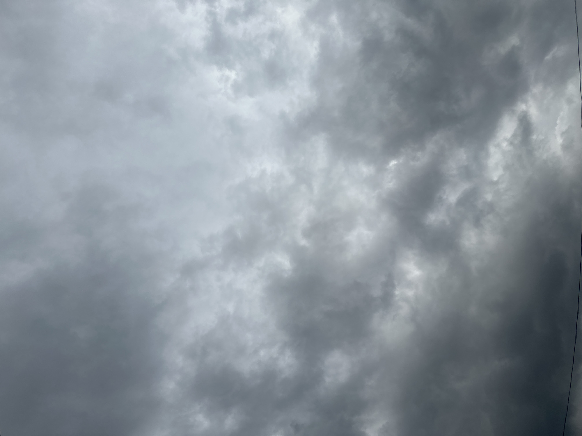 An overcast sky fills the frame, characterized by a dense layer of grey clouds. The lighting suggests it is daytime, but the thick cloud cover diffuses the sunlight, creating a muted and somber atmosphere. The clouds appear textured, with variations in shade indicating depth and thickness. There are no visible structures, people, or any elements that would place this scene within a specific city or location, including Moscow, Russia. The image is solely focused on the sky and its cloud formations.