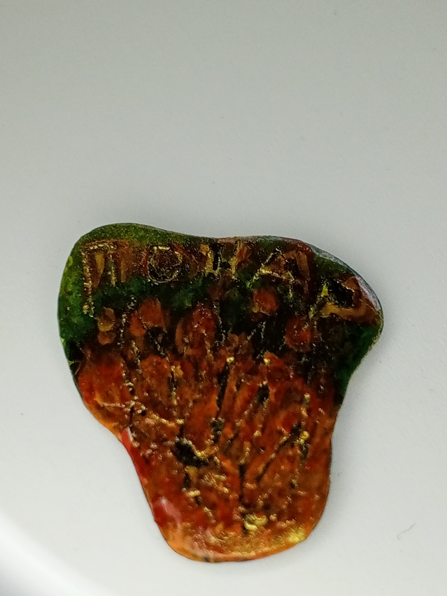 A close-up of a semi-transparent object with an irregular shape is presented against a plain white background. The object exhibits a gradient of colors, transitioning from green at the top to orange and brown towards the bottom. The surface is marked with irregular lines of a gold-like color. The word "WATSON" is written on the top edge. The scene does not provide any information about a location in Bangkok, Thailand.