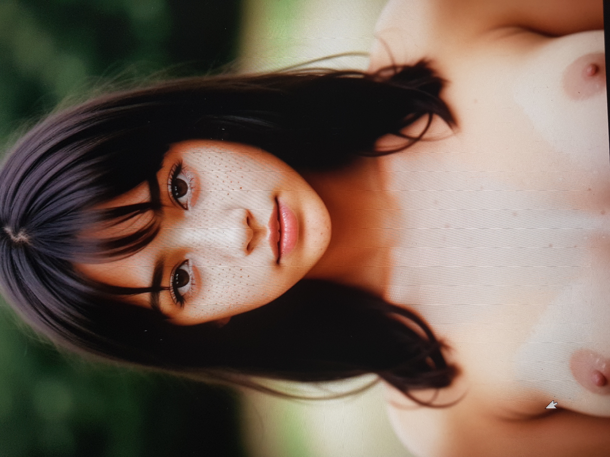 This media file is a photograph of a person lying down, with their head turned towards the camera. The subject has dark hair and is wearing a light-colored garment that exposes their upper body. The background appears to be outdoors, with blurred green foliage suggesting a natural setting. The lighting suggests it is daytime, possibly with soft, diffused light. The subject's expression is neutral. There are no visible objects or text in the image, and no specific activity is apparent other than posing for the photograph. The location context provided is Zherebkove, Ukraine, but there are no explicit visual cues within the image to confirm this.