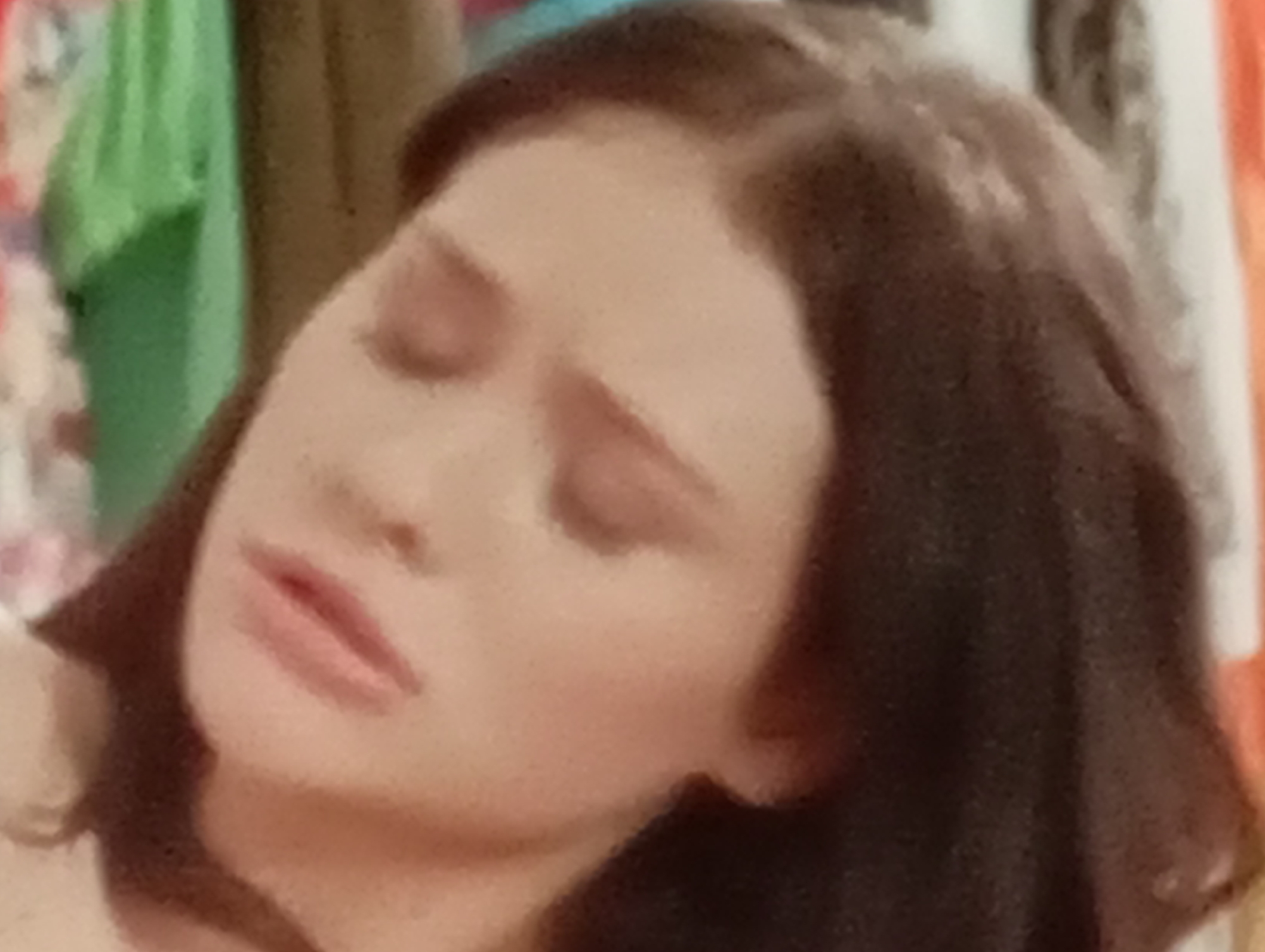 The image shows a close-up of a young woman's face, tilted to the side with her eyes closed. Her hair is dark brown and parted in the middle. She appears to be wearing light-colored clothing. The background is out of focus, with hints of colorful fabric and a neutral wall. The lighting suggests an indoor setting. There is no information about the location in Sofiivska Borshchahivka, Ukraine.