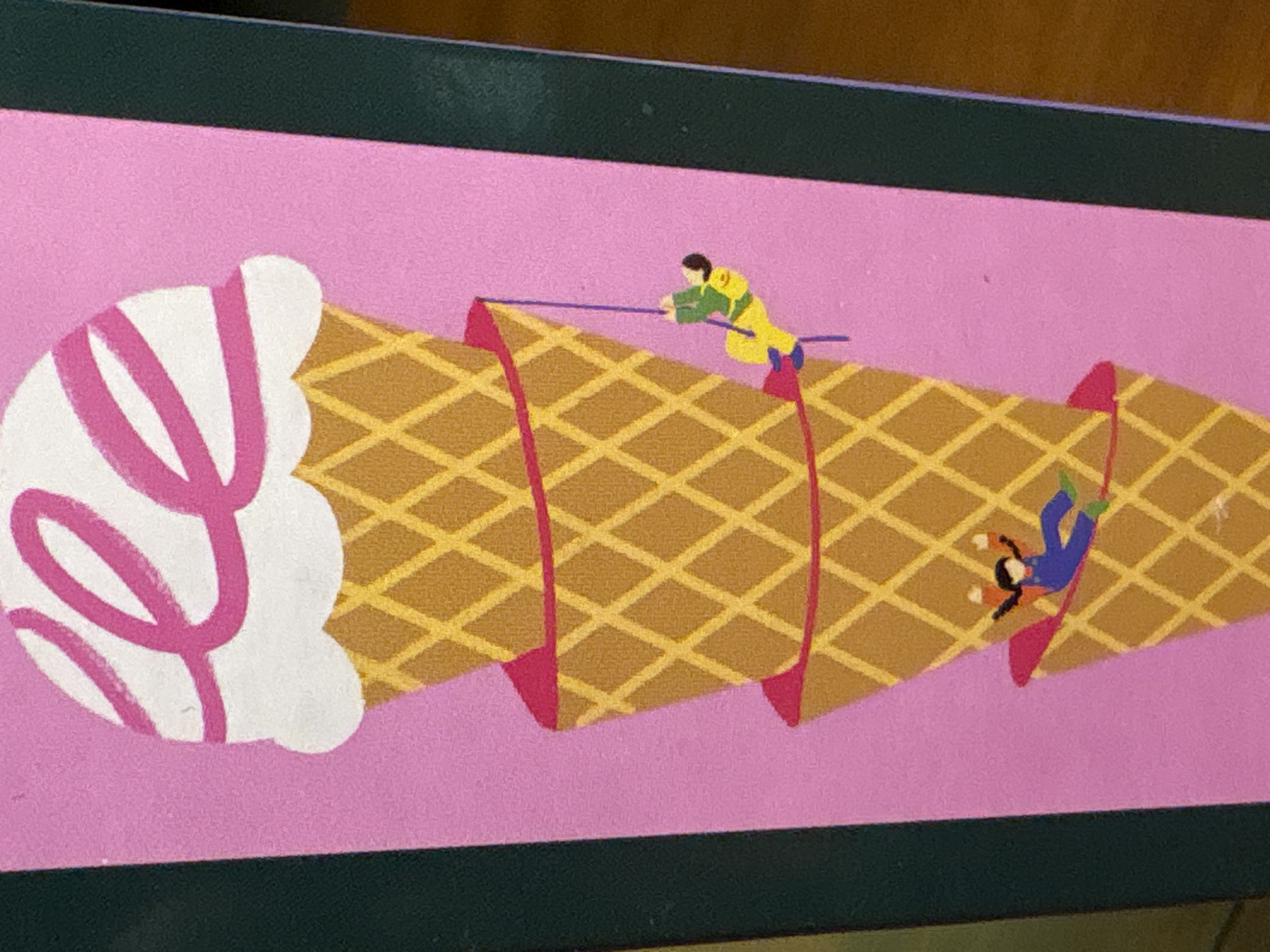 The image is a close-up of a graphic illustration featuring a stack of three ice cream cones on a pink background. The top ice cream cone is topped with white ice cream adorned with pink swirls. Below it, two smaller ice cream cones are stacked, each with a pink base.
The illustration includes two miniature figures: one is depicted climbing down the middle ice cream cone using a purple rope, wearing a green top and yellow pants. Another figure, wearing a blue jumpsuit and orange top, is shown seemingly falling or sliding down the bottom ice cream cone. The style is cartoonish and playful.
This image does not depict a scene in Nha Trang Ward, Vietnam. It is an isolated graphic without any recognizable environmental context that would link it to a specific location.