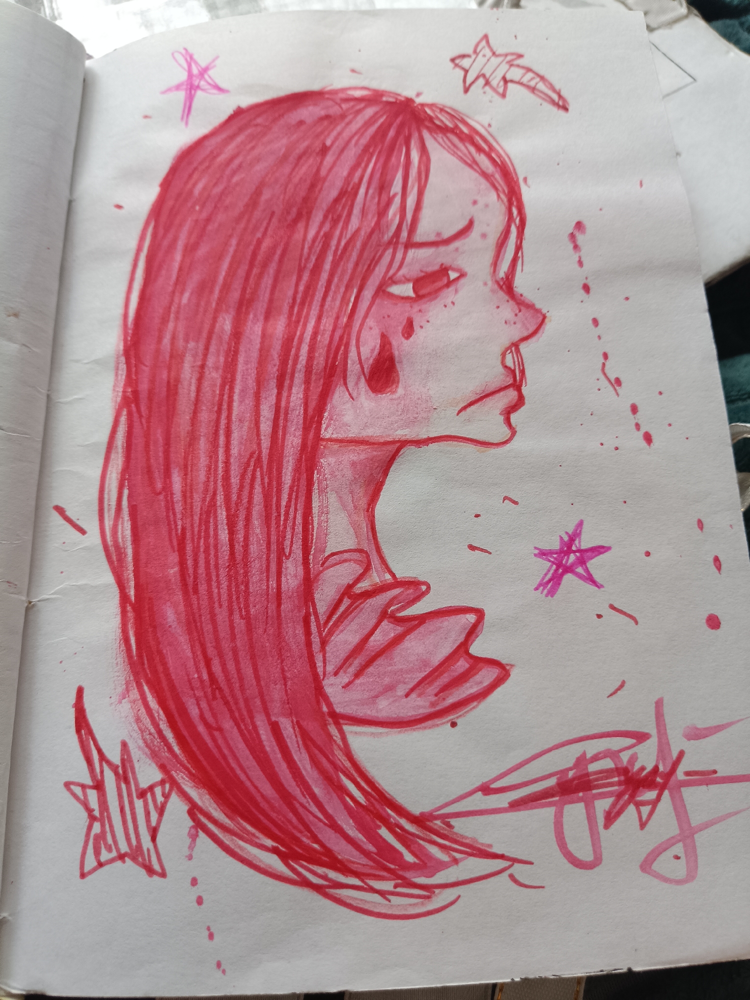 The image is a watercolor sketch of a sad-looking girl with long pink hair. She is drawn in profile with a teardrop falling from her eye. There are pink splatters and stars drawn around her. The drawing is on a white, slightly wrinkled piece of paper. The environment is a sketchpad. The location of this image in the city of Посад, Russia is not specified or inferable from the image itself.