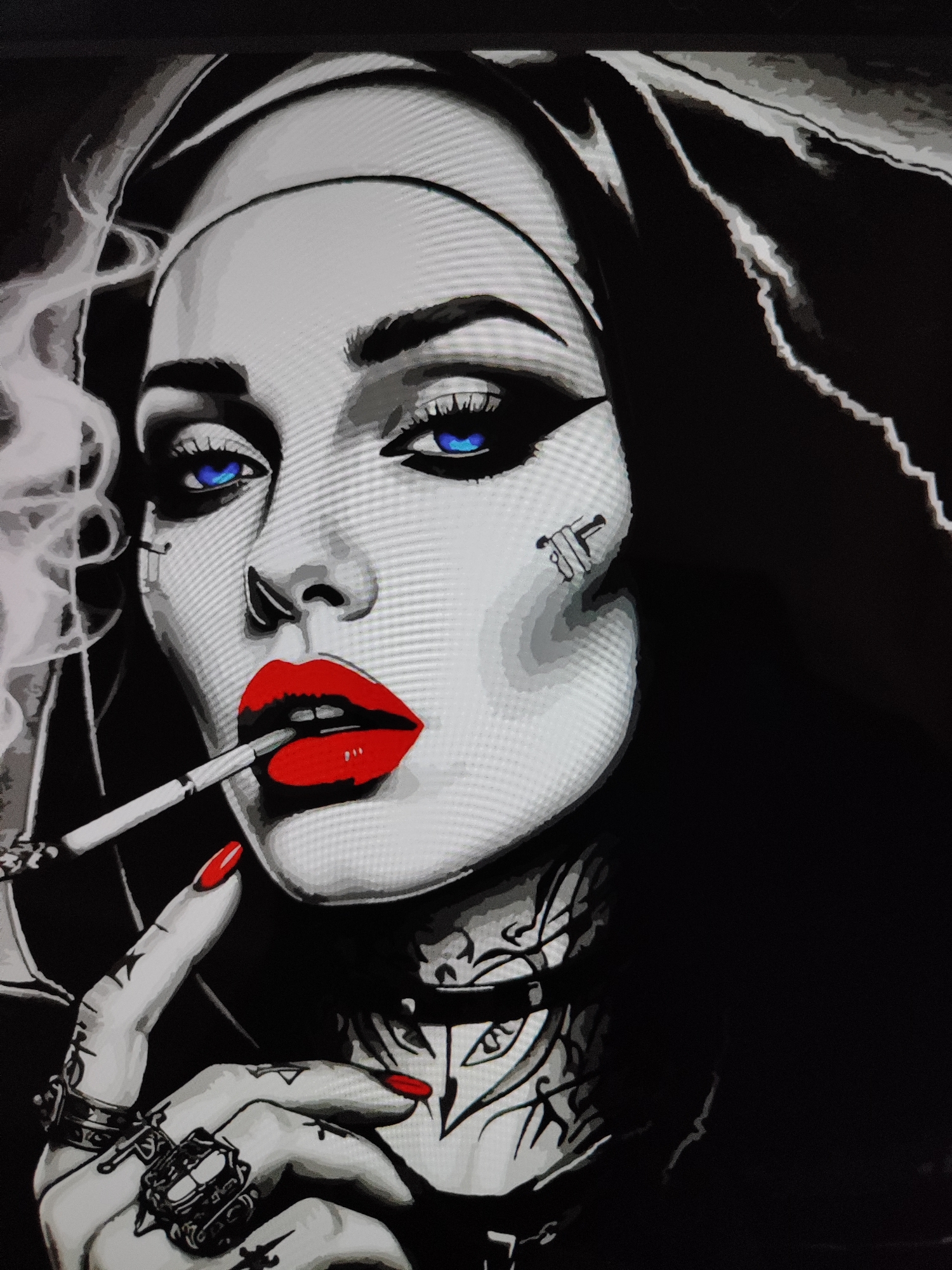 The image is a close-up, stylized portrait of a woman. She has bright blue eyes, red lipstick, and dark hair. She is holding a cigarette in her hand, which is also painted with red nail polish. The woman has tattoos on her neck and hand, and she is wearing rings on her fingers. Smoke is rising from the cigarette. The background is dark and abstract, with some wavy lines suggesting movement or energy. The overall aesthetic is edgy and artistic, with a strong contrast between black, white, and the vibrant colors of her eyes, lips, and nails. There is no indication of a specific location, city, or country in the image.