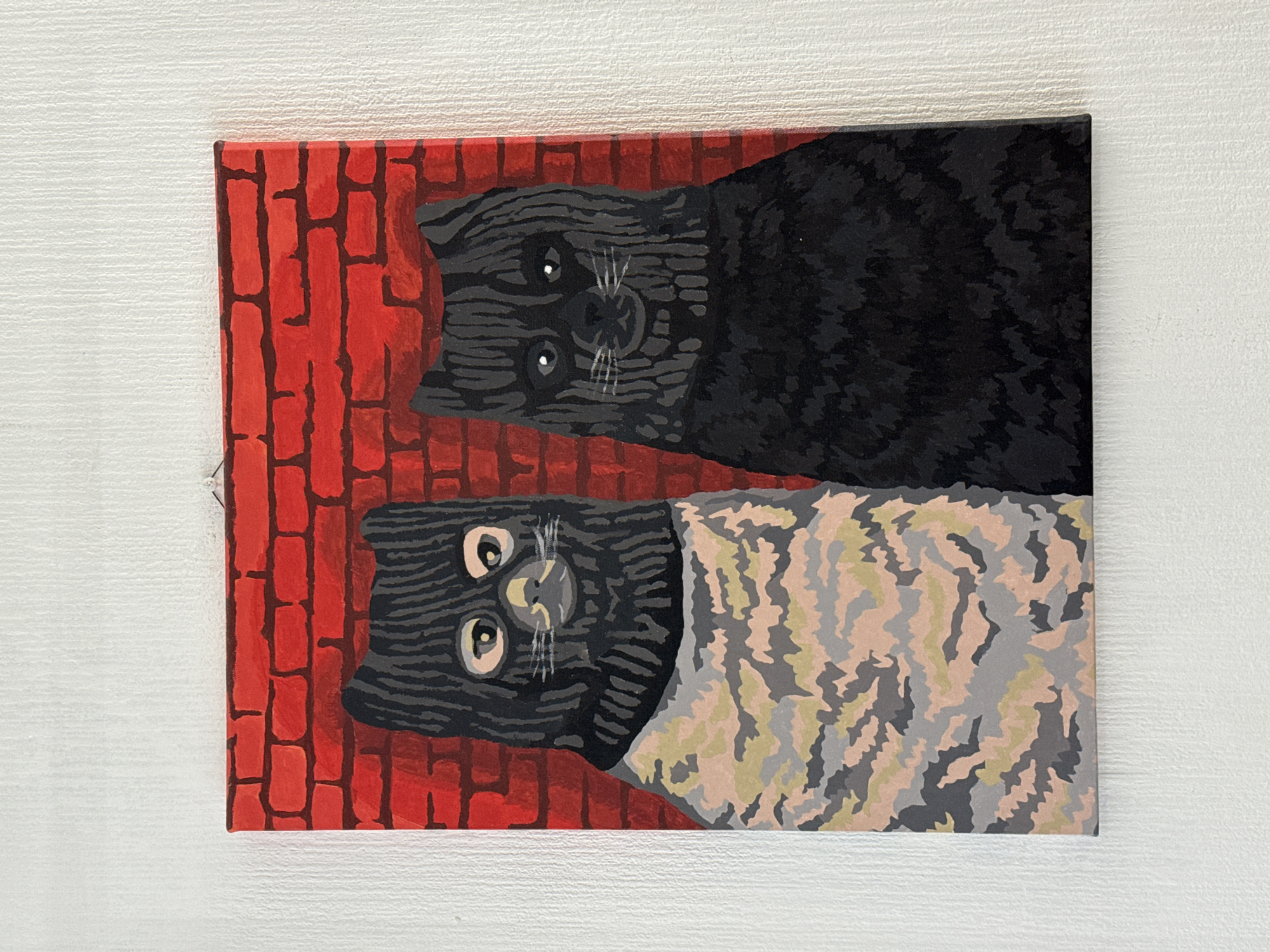 This image features a vibrant, stylized painting of two cats, presented on a canvas that is rotated 90 degrees clockwise from its natural orientation, displayed against a textured white wall.
Within the painting, the two cats are depicted vertically, with their heads facing upwards and their bodies extending downwards. Both cats are shown from an overhead perspective, looking directly forward with large, expressive eyes.
The upper cat is rendered in shades of dark grey and black, with distinct lighter grey stripes creating a textured fur pattern. Its face features large, round, light-colored eyes with dark pupils and small white highlights, complemented by fine white whiskers.
The lower cat shares similar facial characteristics – a dark grey head with lighter stripes, prominent eyes, and white whiskers. However, its body is enveloped in a multi-toned, abstract pattern resembling camouflage, incorporating shades of light grey, dark grey, pale pink, and light green.
The background behind both felines is a bold red, designed with dark outlines to mimic a brick wall. The artistic style is distinctively flat and cartoonish, utilizing block colors and clear lines. No specific activity is taking place, as it is a static piece of art. There is no visible text within the painting. The location context provided for this media file is Saint Petersburg, Russia.