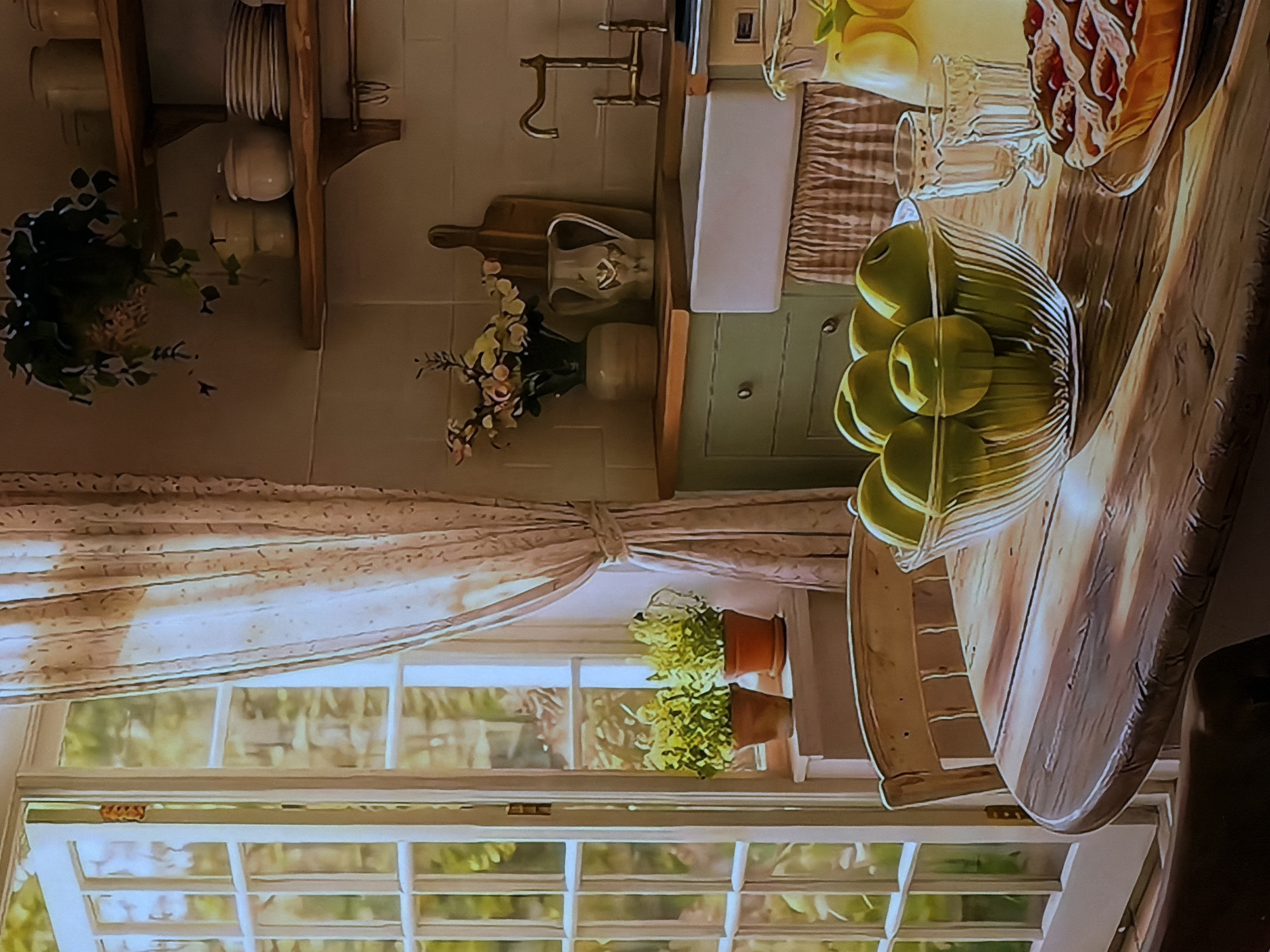 This image, set in a cozy kitchen and dining area in Sofiivska Borshchahivka, Ukraine, depicts a brightly lit domestic scene, likely during the daytime. The perspective is rotated, showing a multi-paned window on the left, a kitchen counter and sink on the right, and a wooden dining table in the foreground.
The kitchen section features light green lower cabinets and a white farmhouse-style sink with a brass-toned faucet. Above the sink, a rustic wooden shelf displays white plates and bowls. A wooden cutting board and a decorative white pitcher are placed on the counter, alongside a vase holding light-colored flowers and another ceramic pot.
On the left, a large, white-framed window allows abundant natural light into the room, revealing lush greenery outside. A sheer, light-colored curtain is tied back, and two terracotta pots with green plants are arranged on the windowsill, adding to the room's inviting ambiance.
The wooden dining table in the foreground is laden with items, suggesting readiness for a meal or gathering. A clear, ribbed glass bowl is filled with vibrant green apples. Nearby, a glass pitcher holds what appears to be lemonade with lemon slices, accompanied by an empty glass. A baked item, possibly a pie or tart with a lattice crust, rests on a wooden serving board. A part of a light-colored wooden chair is visible next to the table. The scene evokes a peaceful and homey atmosphere. No visible text is present in the image.
