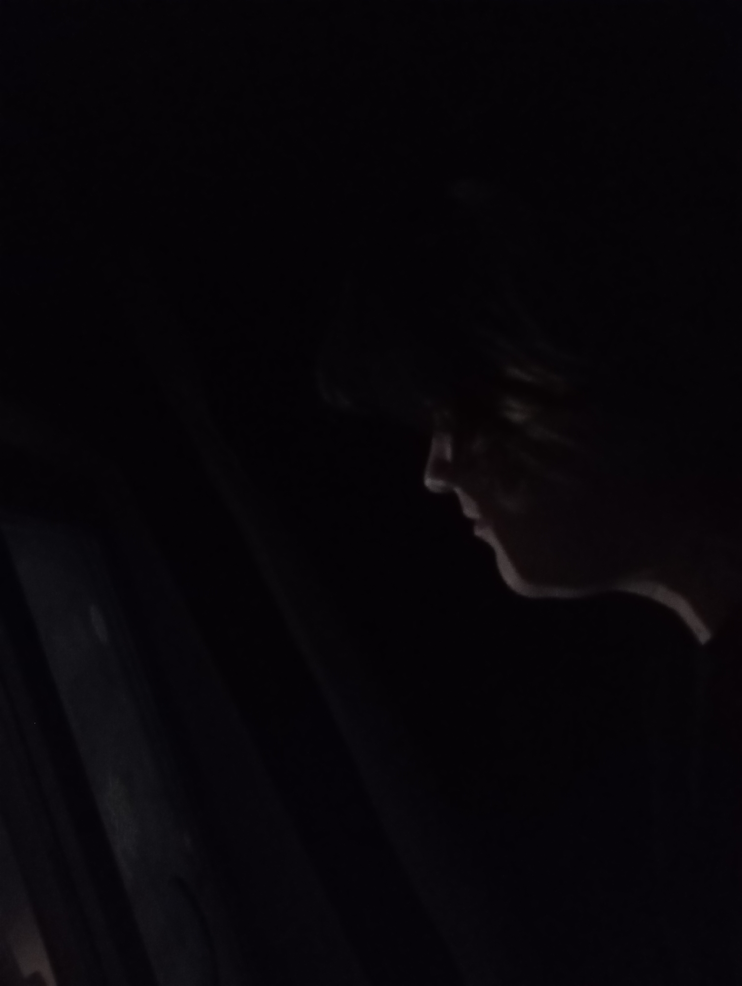 A person's profile is partially illuminated in a dark setting. To the left, there is a dark, shadowed area that appears to be a door or window with indistinct features. There is no way to know anything about the location of Фоки, Russia.