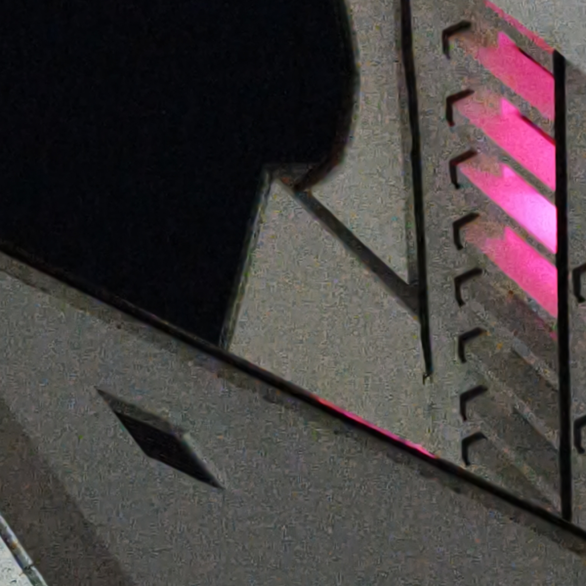 The image displays an abstract, forensic-style view of a building facade at night, specifically identified as belonging to the Oktyabr Cinema in Hrodna, Belarus. The primary visible surface is a textured, light gray material, likely concrete or stone, occupying the lower and central portions of the frame. To the right, a vertical architectural feature presents a series of six horizontally oriented, glowing pink light strips, each enclosed within a dark, L-shaped bracket or frame. These illuminated elements are evenly spaced. Below the center, a dark, sharp-edged rhomboid shape is integrated into the gray facade. Dark, angular structural lines and shadows intersect various planes, contributing to the geometric composition. The upper left and parts of the mid-left area are a deep black, indicating either the night sky or a heavily shadowed section of the building. The scene is devoid of people, subjects, or observable actions, focusing solely on the architectural details and artificial illumination in a low-light environment.