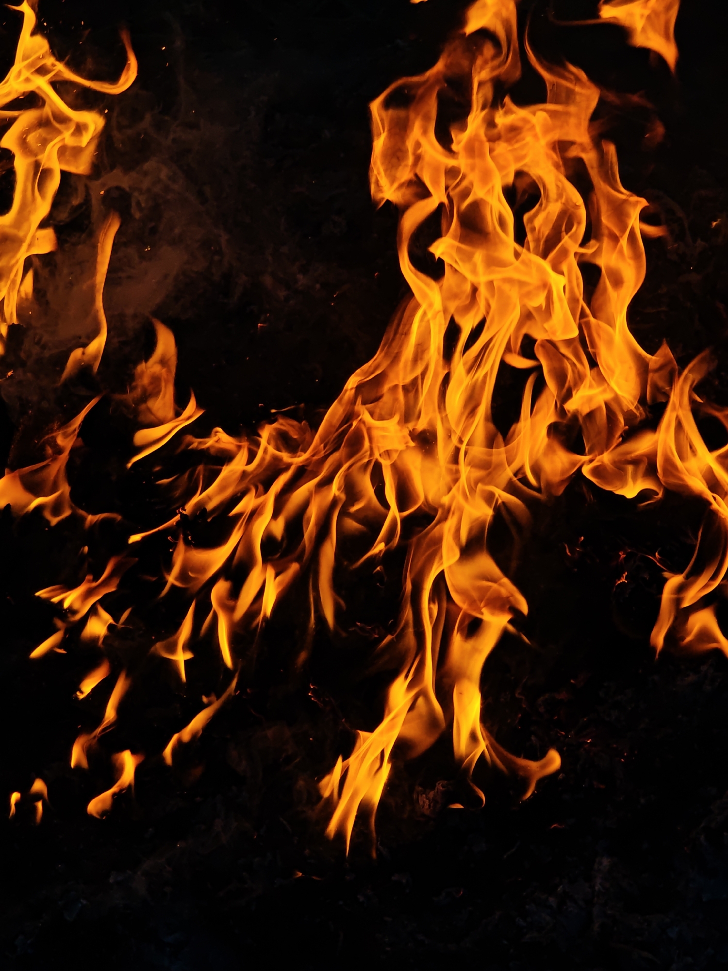 The image depicts a close-up view of flames. The flames are primarily orange and yellow in color, with varying intensities of light. The background is black, creating a stark contrast that highlights the fire. There is no indication of the location being Parkhomivka, Ukraine or any other city. No people, objects, or actions are visible other than the fire itself.