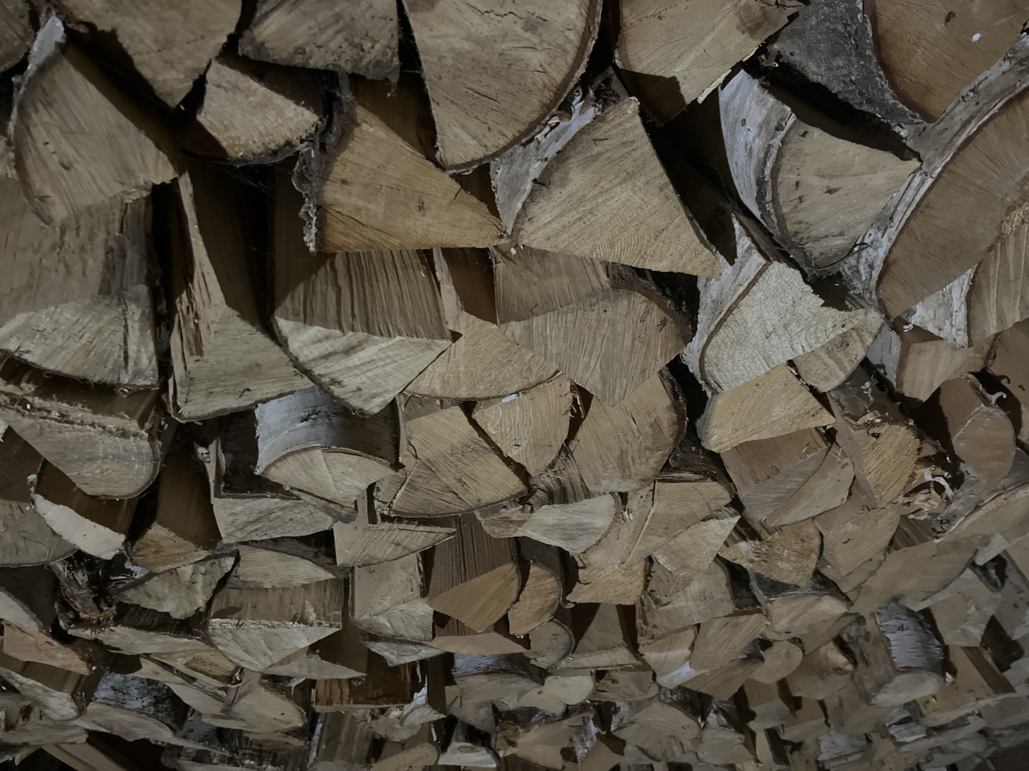 The image shows a stack of cut firewood, likely for heating. The wood pieces are mostly quartered sections of logs, arranged in a dense pile. The wood appears to be seasoned, with variations in color and texture. There is no visible evidence of human activity or any other specific objects or subjects within the immediate frame. The image lacks any context to place it in Malyi Bukor, Russia or to infer any specific location. The description is based solely on the visual elements present in the provided image.