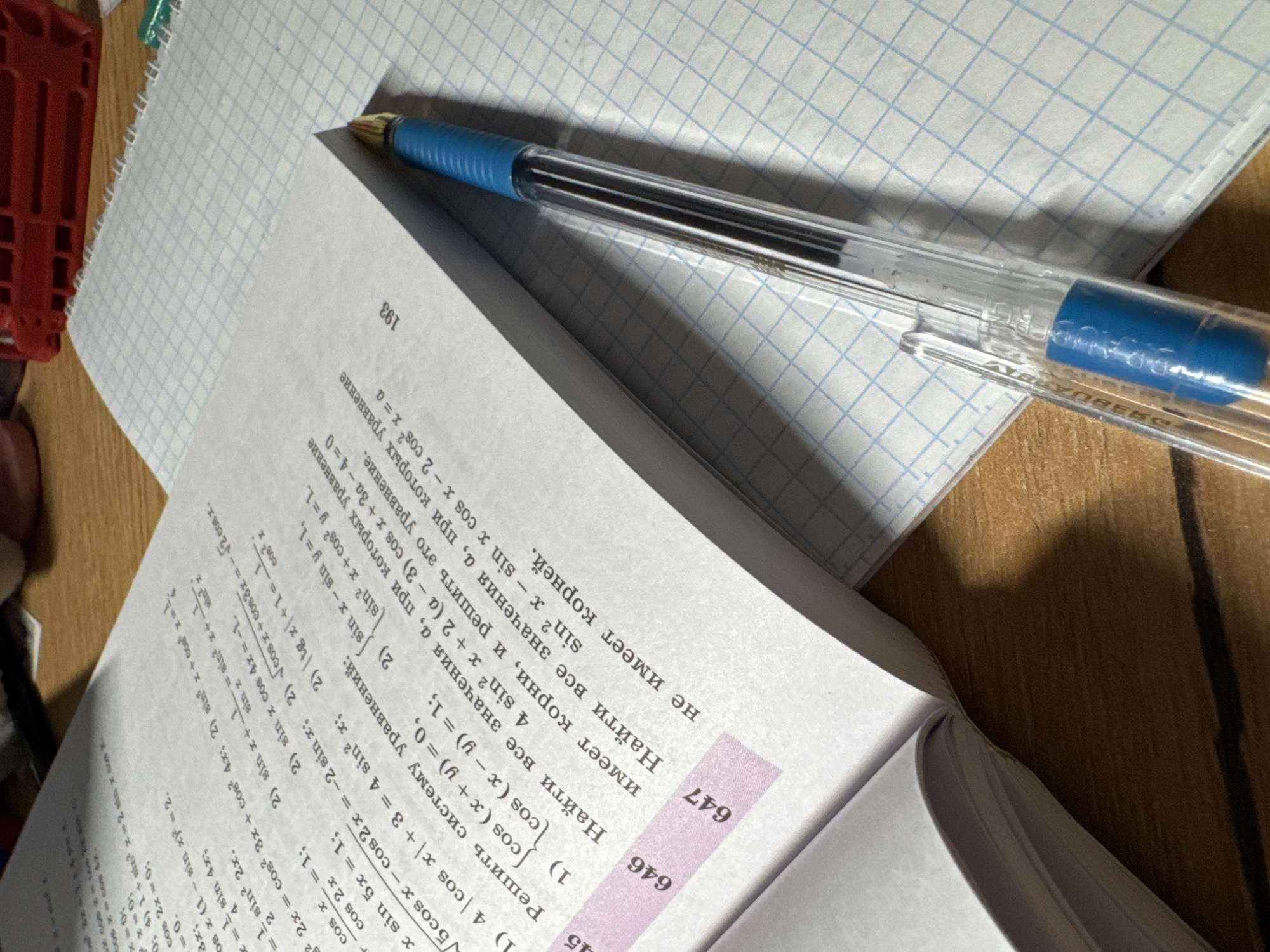 The image shows an open textbook with mathematical problems written in Russian, next to a blue pen and a notebook with a grid pattern. The textbook is turned towards the viewer, with the right-hand page visible. The problem numbers 646 and 647 are printed in a pink box on the open page. The number "193" is printed at the top right corner of the facing page, which is slightly folded.