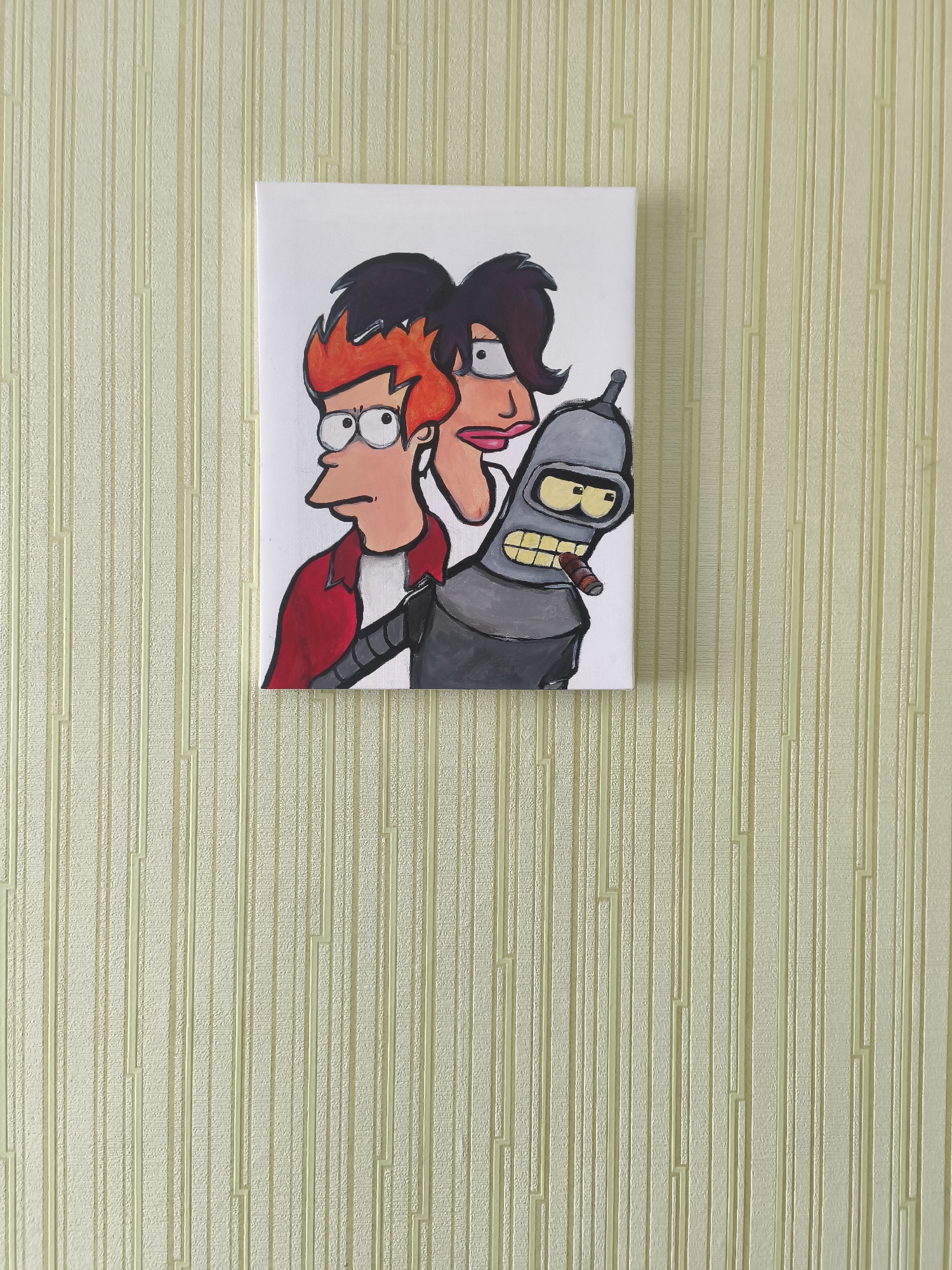 A framed painting featuring characters from the animated series Futurama hangs on a textured, light yellow wall. The painting depicts three characters: Philip J. Fry, Leela, and Bender Bending Rodriguez, who is smoking a cigar. The background of the painting is white. The wall has a vertical, ribbed texture. The image was taken indoors, with no indication of the specific location in Minsk, Belarus.