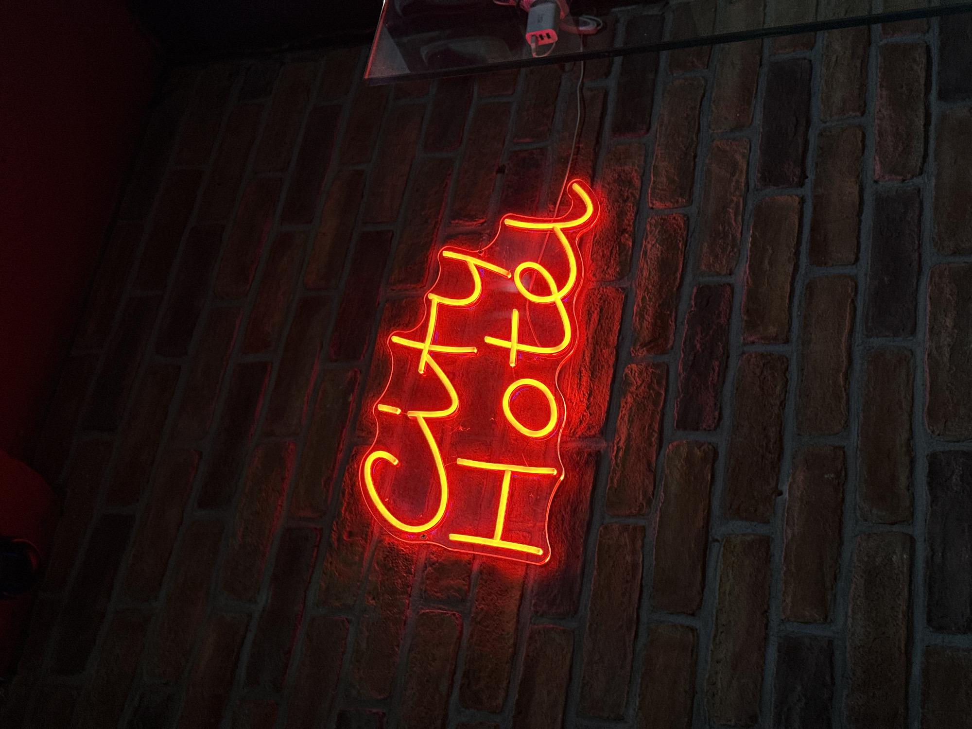 A red neon sign that says "CxA Hotel" hangs against a brick wall. The brick wall appears to be interior. The location is implied to be a hotel based on the sign. The location of the hotel is Veliko Tarnovo, Bulgaria.