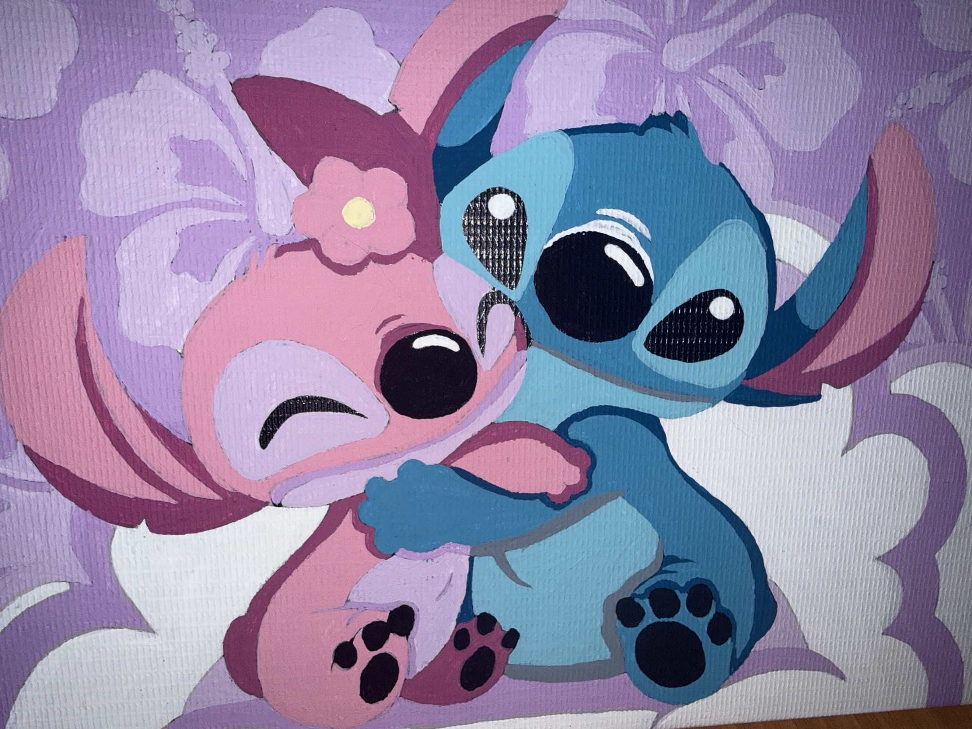 A painting depicts two cartoon characters, Stitch and Angel, hugging. Stitch, colored blue, is on the right, and Angel, colored pink, is on the left. They are depicted with large black eyes with white pupils. Angel has a yellow flower on her head. The background is purple with light purple and white hibiscus flowers. The painting is on a canvas with a visible texture. There is no information about the city of Rayevskiy, Russia in the image.