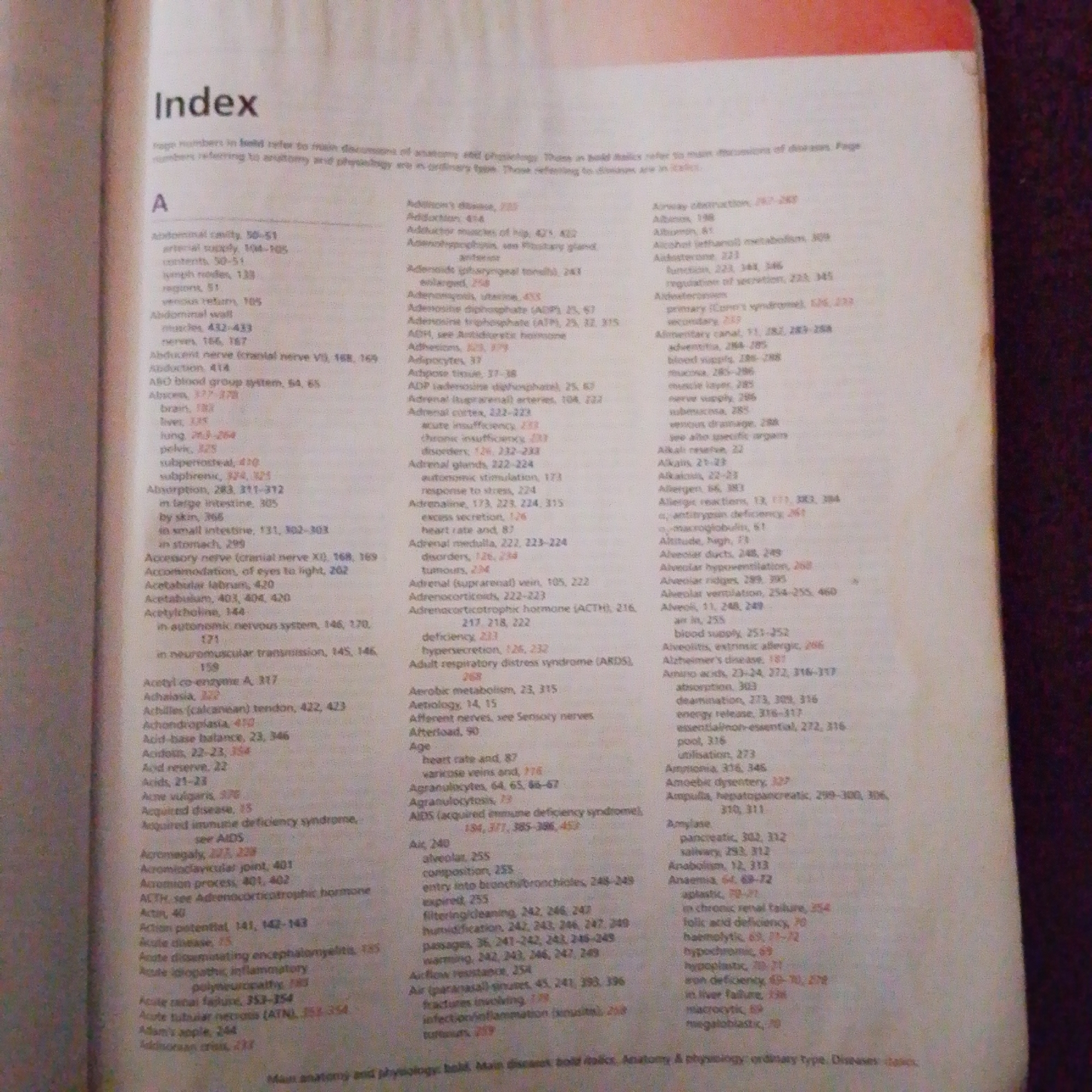 The image displays a section of an index from a book. The index is organized alphabetically, with a prominent "A" heading. The text consists of entries related to anatomical and physiological terms, followed by page numbers. Some entries are in bold italics, which the index key indicates refer to main discussions of disease. The surrounding background is blurred and appears to be a dark, possibly textured surface, suggesting the book is resting on an object. There is no visible content in the image that relates to Jalingo, Nigeria, people, actions, or forensic details.
