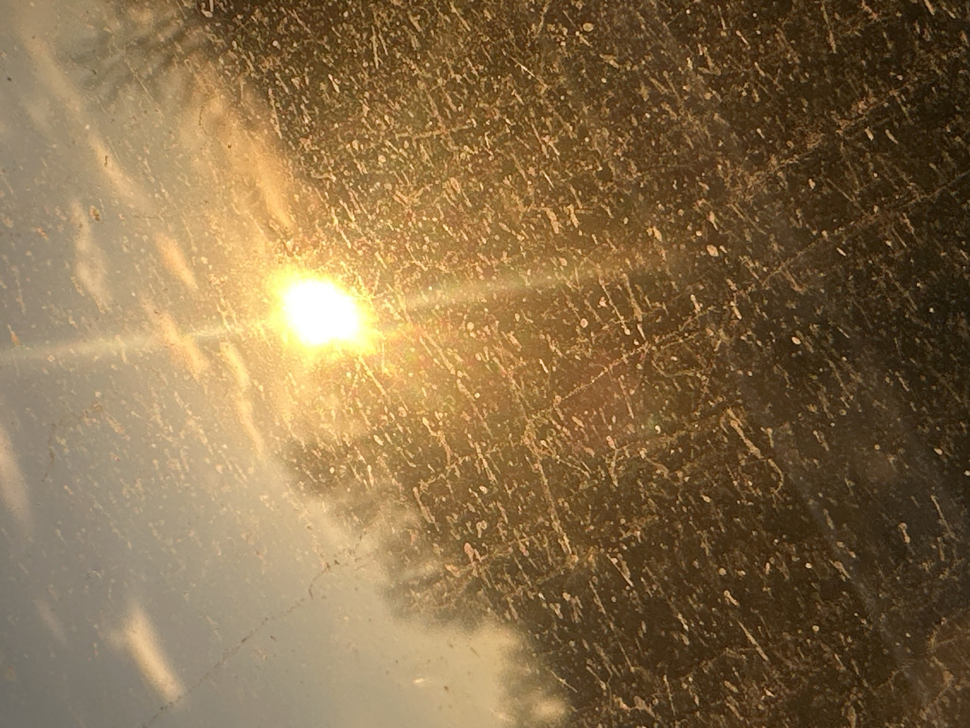 The image shows sunlight shining through a scratched or dirty glass surface. The scratches and dirt create a diffused effect, blurring the light. There is a reflection on the left side of the image. It does not depict a location in Moscow, Russia, nor are there identifiable people or subjects present.