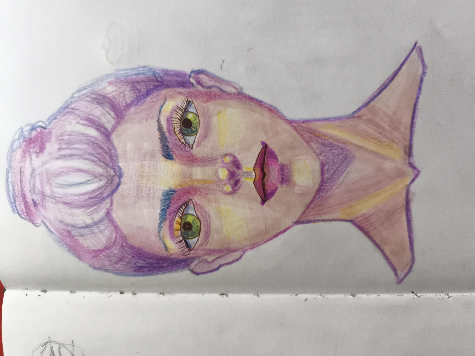 The image is a drawing on a white paper notebook. The drawing is of a stylized head, rendered in pastel colors, primarily pink, purple, yellow, and green. The head is oriented sideways, with the face looking towards the right of the frame. The hair is depicted in shades of purple and pink, styled in voluminous waves. The eyes are large and green with pronounced eyelashes and blue accents around the sockets. The lips are full and painted a vibrant pink. The overall impression is of a whimsical or fantasy-inspired portrait. There is a faint sketch of a profile in the upper left corner of the paper. The bottom edge of the notebook is visible, showing a spiraled binding and some small dark specks on the paper. The drawing does not depict any recognizable landmarks or elements that would indicate a specific location in Saint-Denis, France.