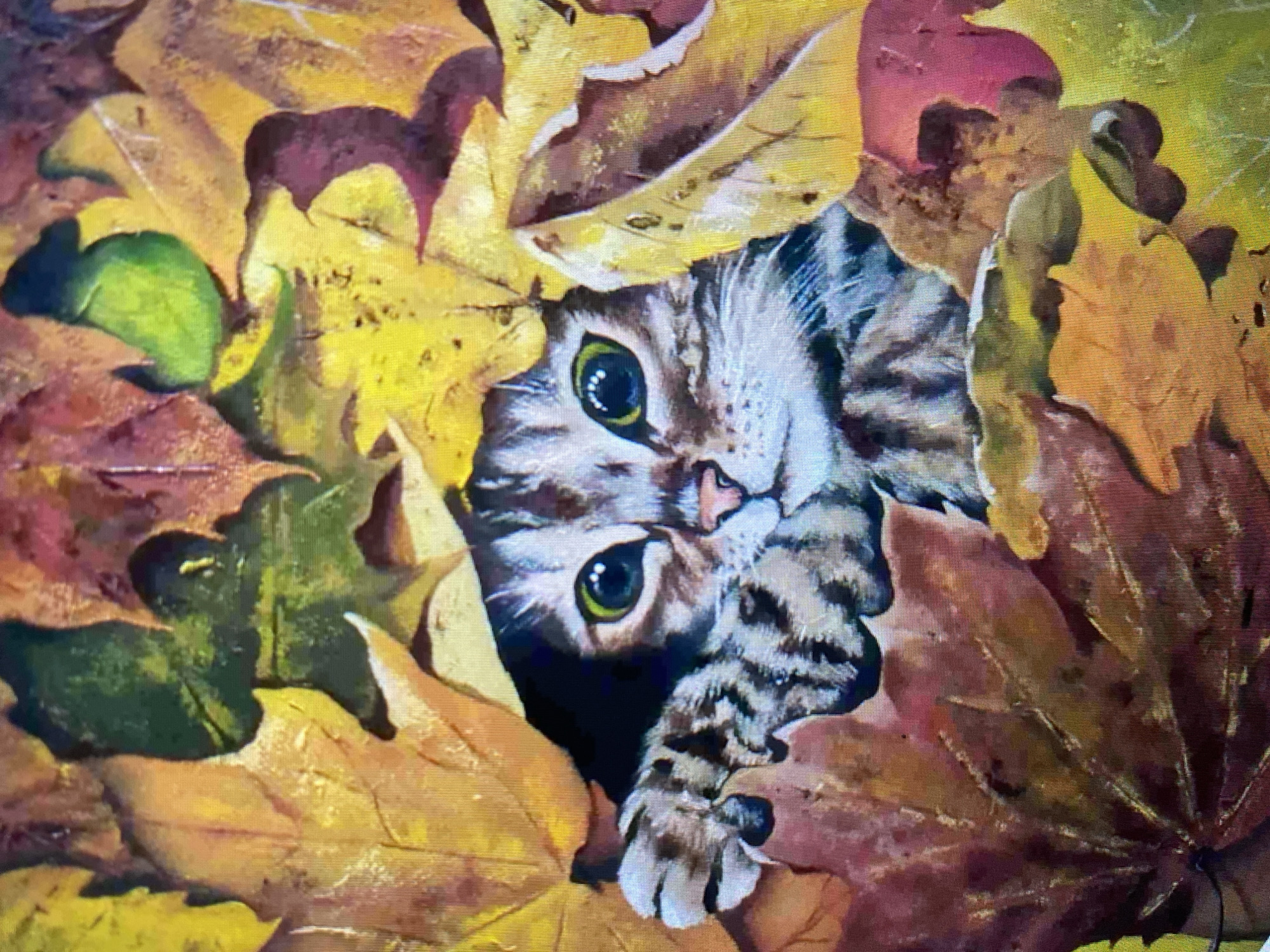 The image is a close-up painting of a tabby cat peeking through a pile of colorful autumn leaves. The cat has large, bright green eyes and its front paw is visible, resting on a leaf. The leaves are a mix of yellow, orange, red, and green, with some appearing to be maple leaves. The background is filled with more leaves, creating a sense of depth and texture. The painting is realistic, capturing the soft fur of the cat and the delicate veins of the leaves. There are no specific details about the location in the city of Unknown, Unknown.