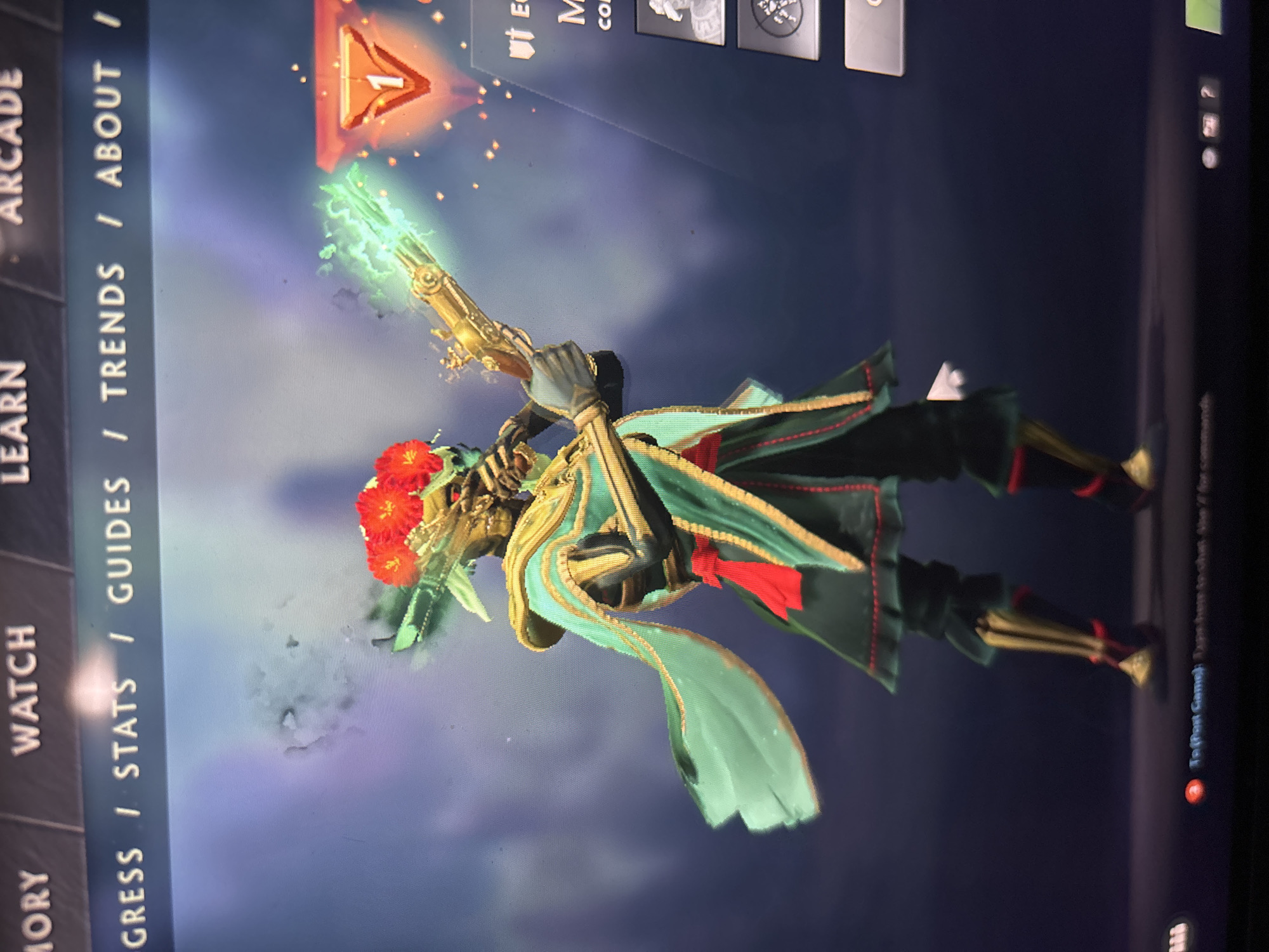The media file captures a vertical screen display, likely from a video game, showcasing an ornate character model against a dark blue and purple gradient background. The character, positioned centrally, is a humanoid figure adorned in an elaborate costume featuring dark green and teal fabrics with red and gold accents. Red flowers form a prominent headpiece on the character's head, and skeletal or mechanical elements are visible on its hands and face. The character holds a golden, antique-style gun that emits a bright, glowing green light from its muzzle, surrounded by small, sparkling particles.
The scene appears to be a character selection or customization screen within the game, indicated by various user interface elements. Along the left edge, a vertical menu bar displays partially visible text: "MORY," "WATCH," "LEARN," and "ARCADE." Further down, text reads: "GRESS / STATS / GUIDES / TRENDS / ABOUT /". At the top-right, a red-orange triangular icon with the number "1" is prominently displayed. Other small, grey icons and fragmented text like "Ut E," "M," and "CO" are also visible at the top. Near the bottom-right, faint text includes "To (Post Game):" and "for commands". The image does not contain any visual cues or elements that indicate a specific real-world location like Sofia, Bulgaria; it depicts a digital, virtual environment.