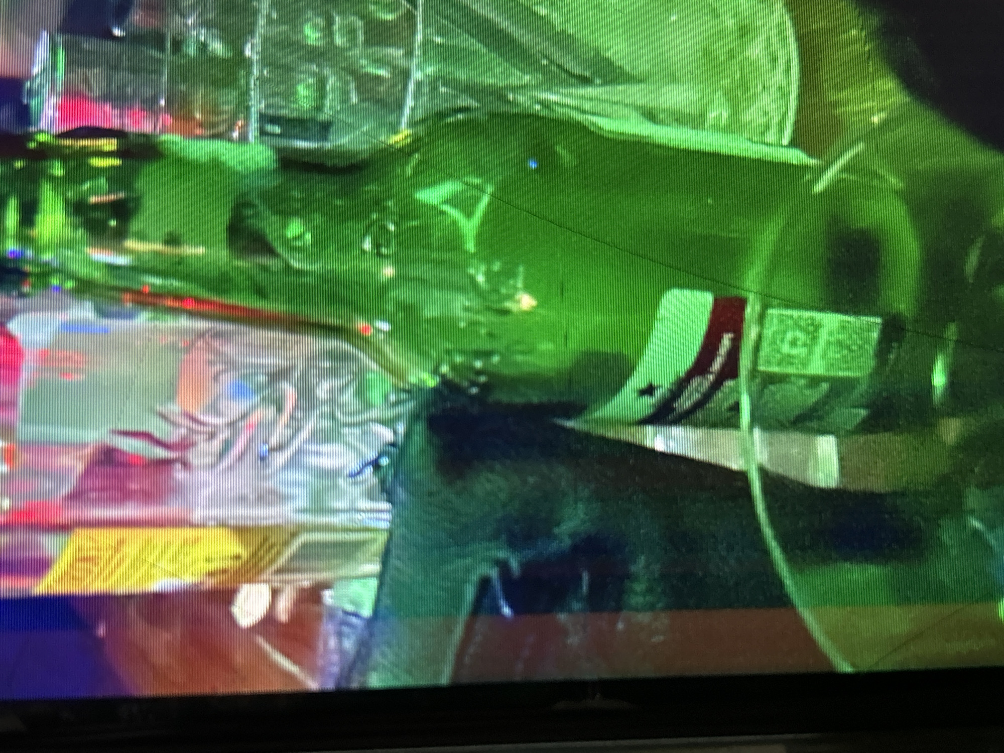 The image depicts a close-up, somewhat distorted view of a green glass bottle, possibly containing a beverage, set against a backdrop of colorful, blurred lights and objects. The bottle is the dominant subject, with its curved form and green hue filling a significant portion of the frame. A label with red and white elements is visible on the bottle. To the left of the bottle, a yellow object, possibly a carton or box, is partially obscured. The background suggests an indoor setting with the appearance of other bottles, glasses, and possibly decorative lights, creating a festive or bar-like atmosphere. The image has a slightly grainy texture, indicating it was taken in low light conditions or with a low-resolution camera. There are no discernible people or specific actions taking place within the frame.
Due to the lack of any recognizable landmarks, geographical features, or distinguishing elements within the image, it is impossible to determine the specific location in Depok, Indonesia, or any other city. The scene is generic and could be found in numerous establishments globally.