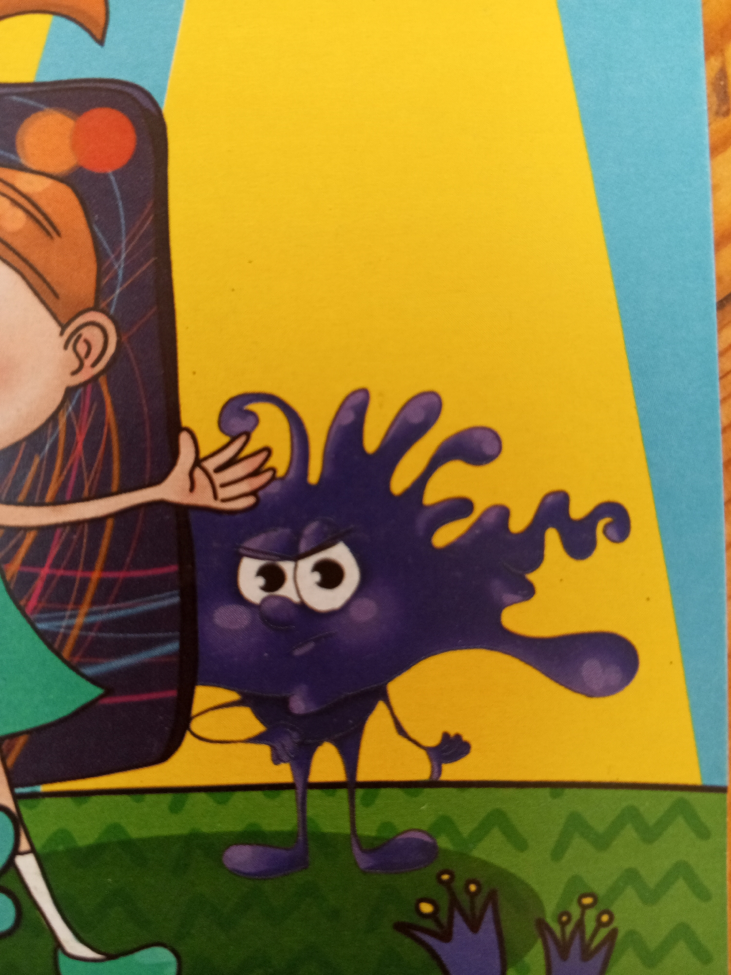 The image shows a cartoon illustration on a yellow background with a blue stripe on the right and a green stripe at the bottom. On the left, a portion of a cartoon character's head and arm is visible. This character has brown hair and is wearing a green shirt. The arm is reaching out towards the right. Next to this character, a purple, amorphous blob-like creature with eyes and a frowning mouth is depicted. The creature has legs and appears to be standing. The environment at the bottom of the image is a green wavy pattern that suggests grass. There is no information in the image that would allow for its location in Chistopol, Russia.