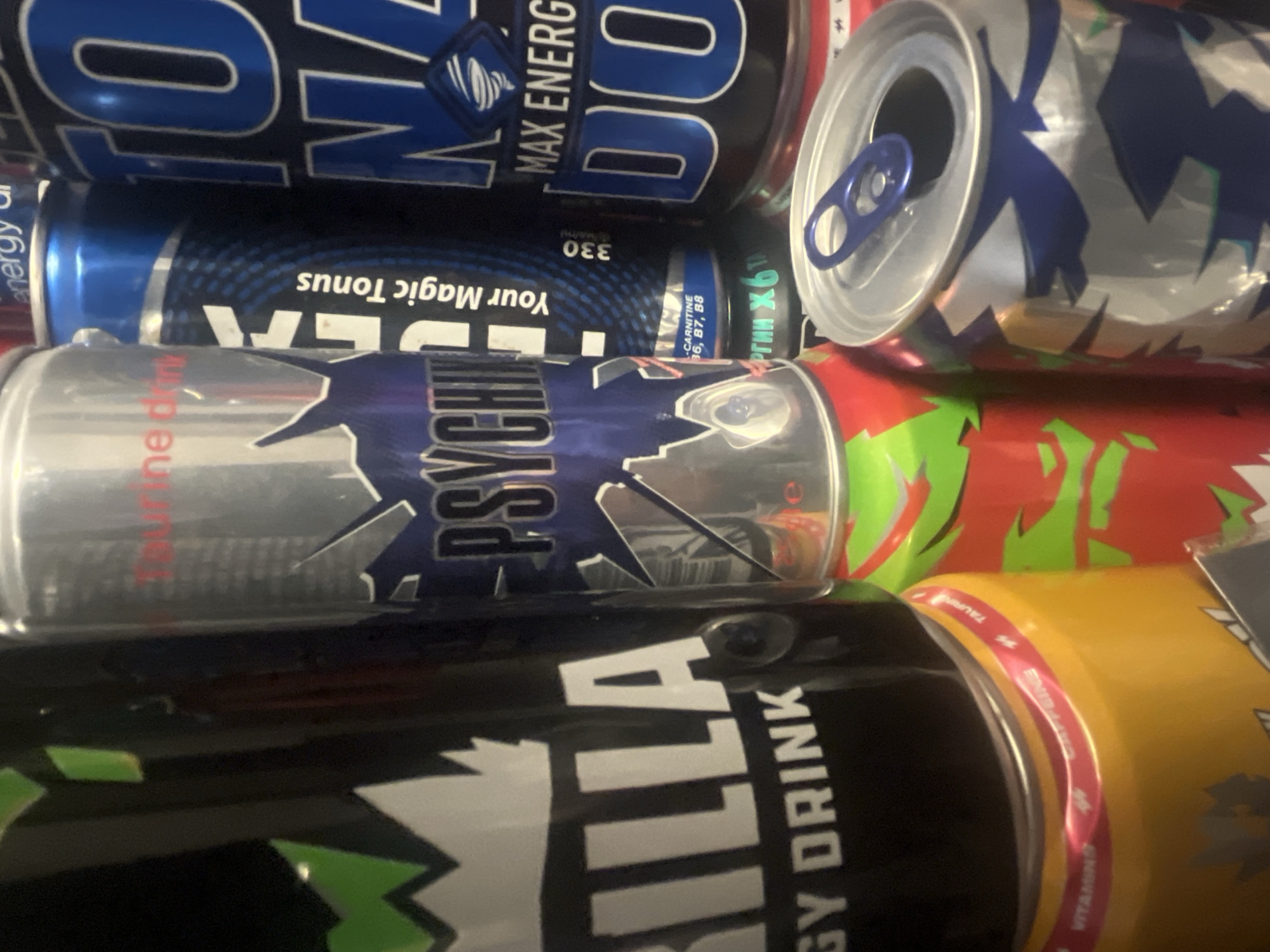 The image shows a stack of energy drink cans. Brands include "MAX ENERGY DO," "IDEA Your Magic Tonus," "PSYCHO," and "Gorilla ENERGY DRINK". The scene's location in Yerevan, Armenia is not visually evident.
