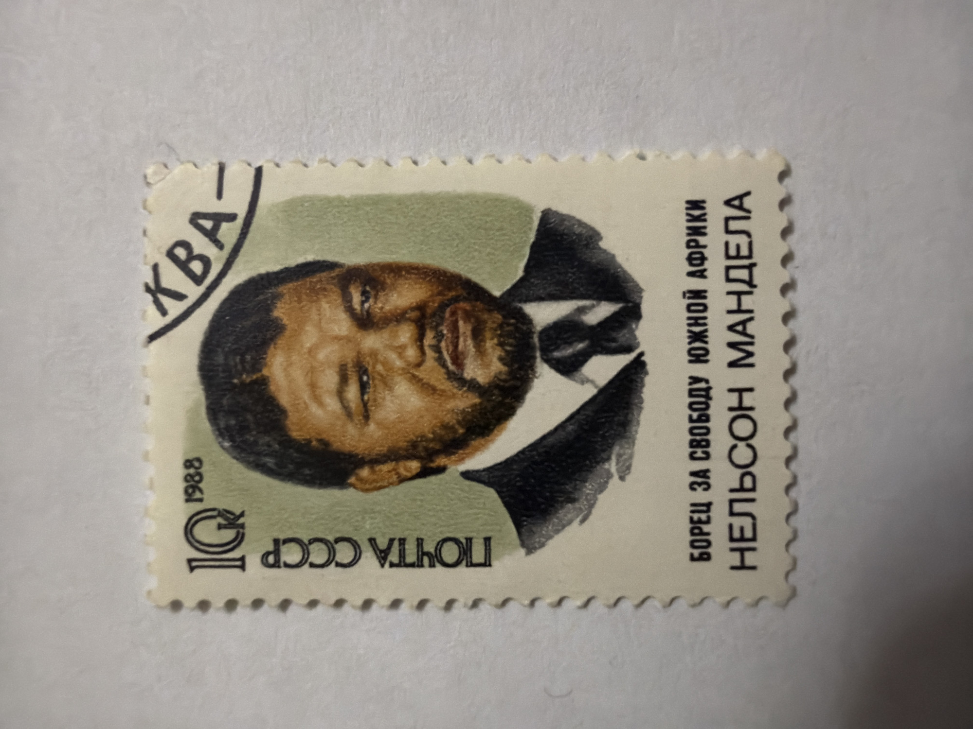The image shows a rectangular, perforated stamp. The stamp is printed in a predominantly beige/cream color with black and brown details. A portrait of Nelson Mandela is featured prominently on the stamp. Mandela is depicted in a suit and tie, his head turned slightly to the side. The text "Москва" (Moscow) is printed in the upper left corner. The text "ПОЧТА СССР" (Postal Service of USSR) and "10K" (10 kopeks) along with "1988" are printed in the lower left corner. On the right side of the stamp is the text "БОРЕЦ ЗА СВОБОДУ ЮЖНОЙ АФРИКИ" (Fighter for the freedom of South Africa) followed by "НЕЛЬСОН МАНДЕЛА" (Nelson Mandela). The location of Izhevsk, Russia is not present in the image.